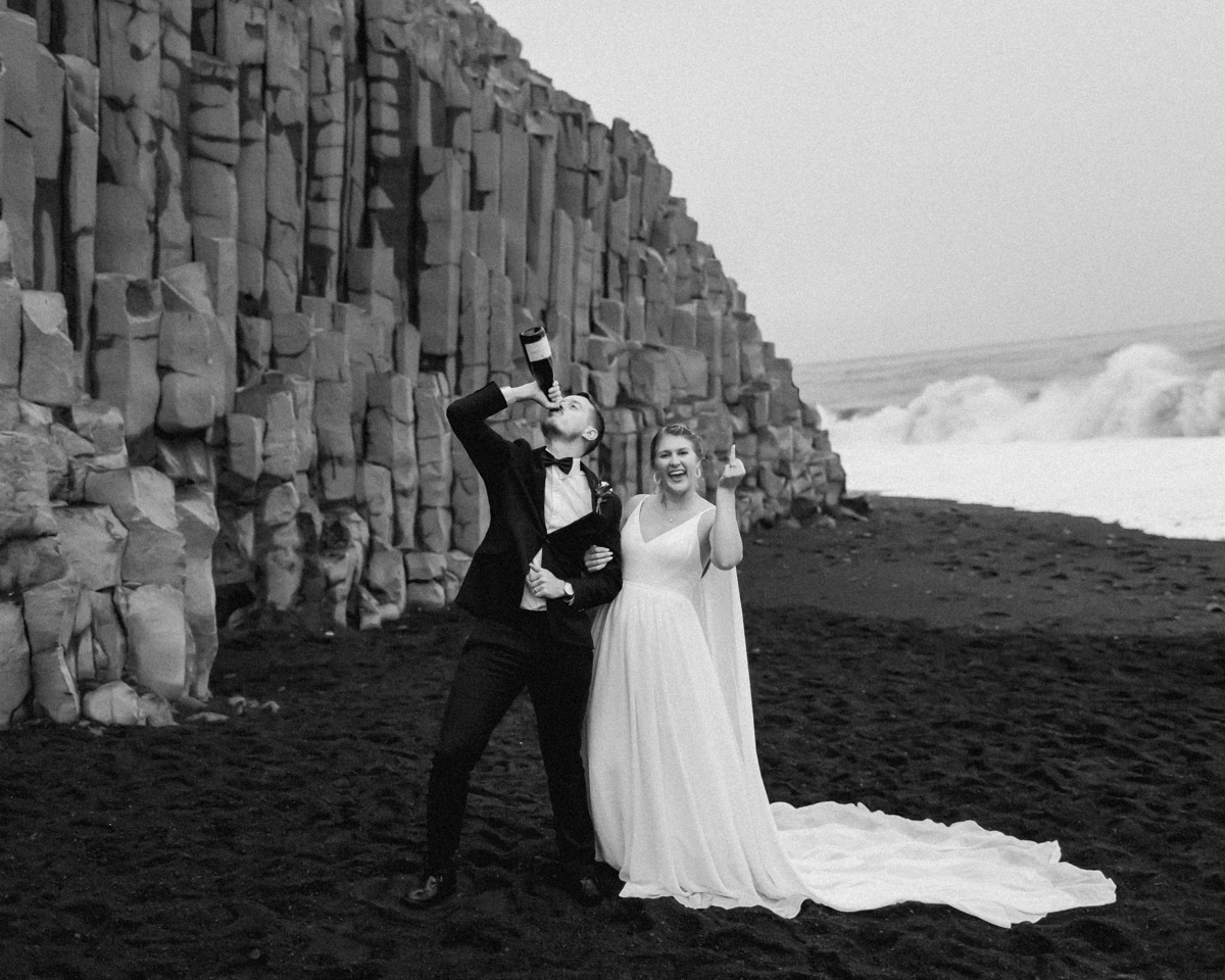 Michael and Nicole celebrate their wedding vows with a champagne pop on the beach during their Iceland elopement 
