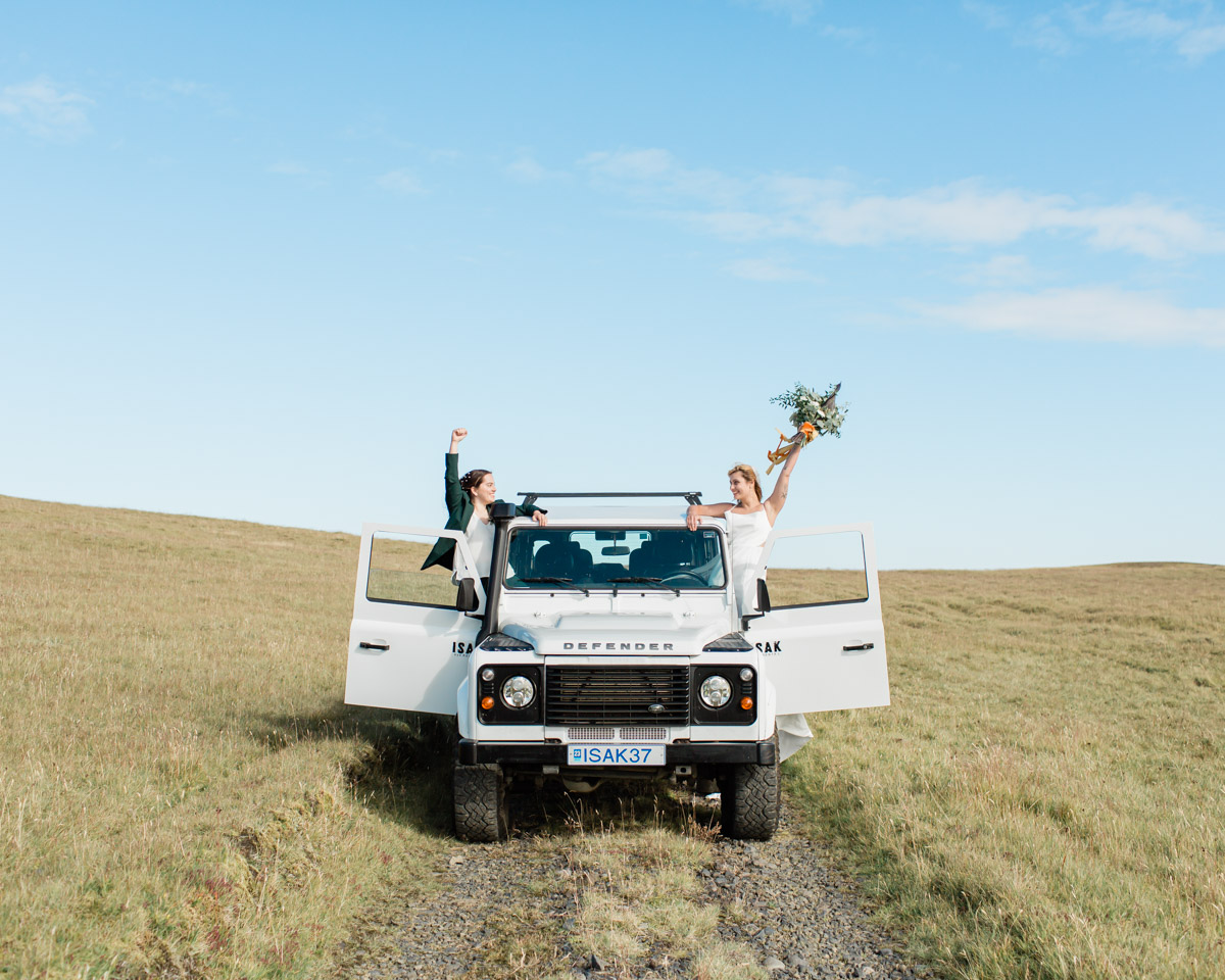 Joanna and Kili celebrating with their hands in the air in their isak 4x4 defender after their wedding vows on their elopement day in Iceland