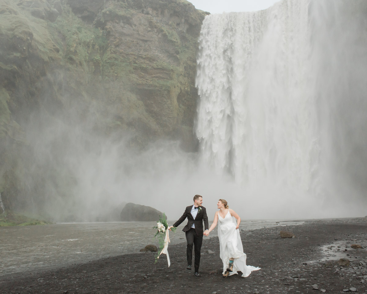 Michael and Nicole have fun skipping in front of an epic waterfall during their Iceland elopement 