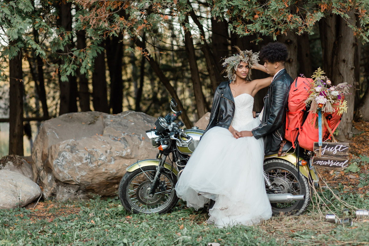 A couple that was just married sitting on their motorcycle on their elopement day, hand in hand