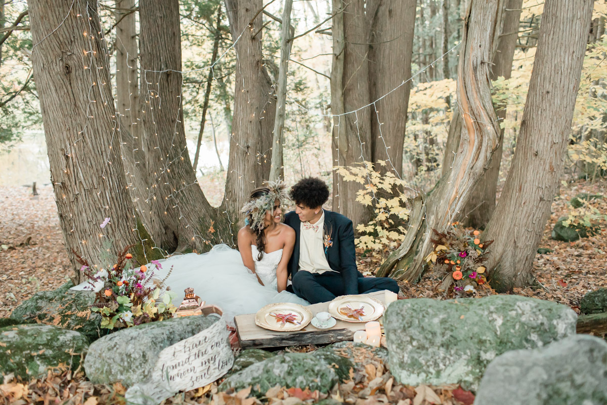 An eloping couple that decided to plan their wedding day in Ontario during the autumn season. They are enjoying a gorgeous picnic in the forest and laughing together. 