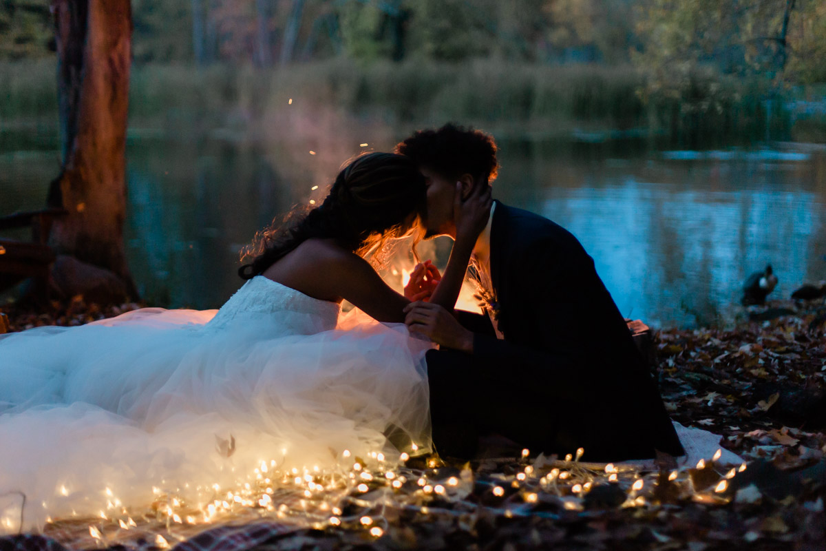 A couple in front of a romantic bonfire at night during their Ontario elopement in the autumn season