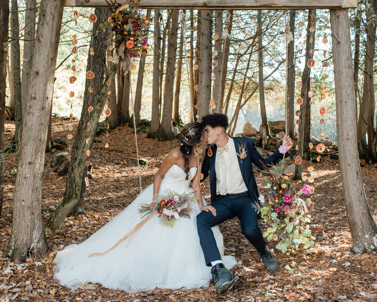 A couple eloping in Ontario for their wedding day at a private camping airbnb. During the fall season they canoed and said their vows under a gorgeous flower arch in front of a pond. 