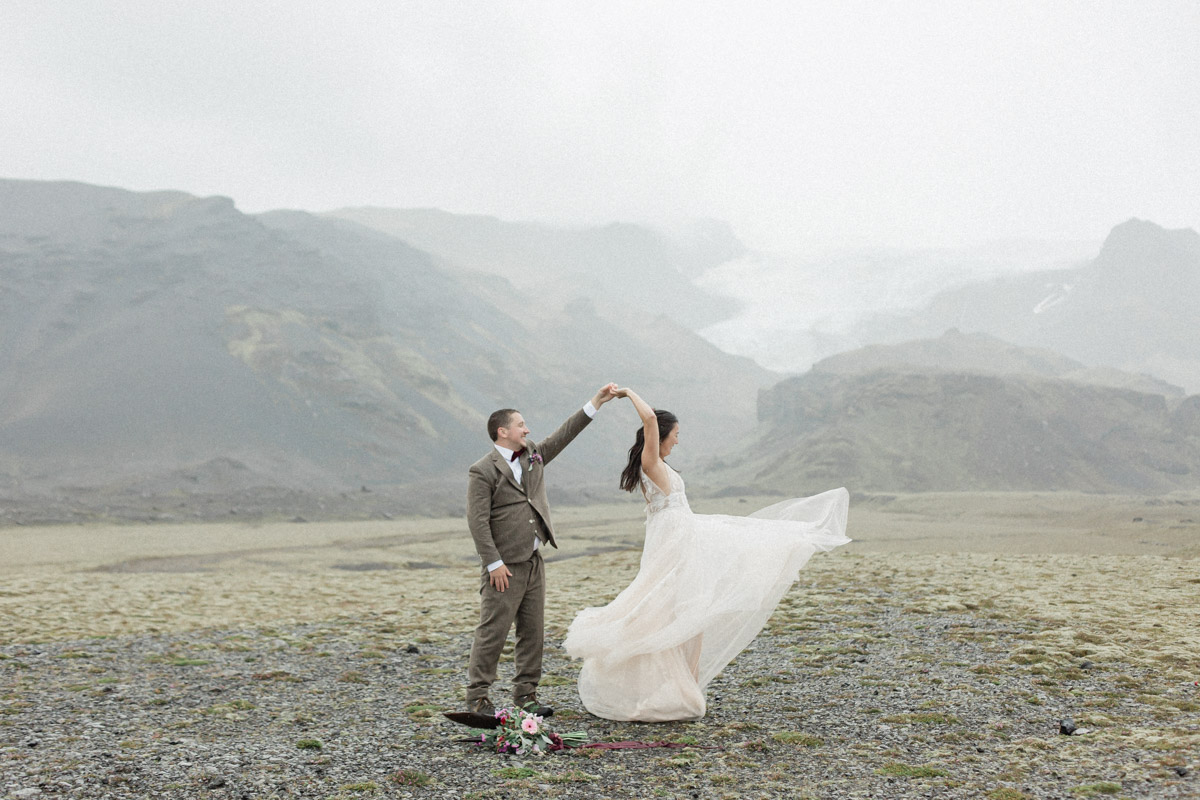 Leah and Darin dancing in their wedding attire in front of a mountain range in Iceland
