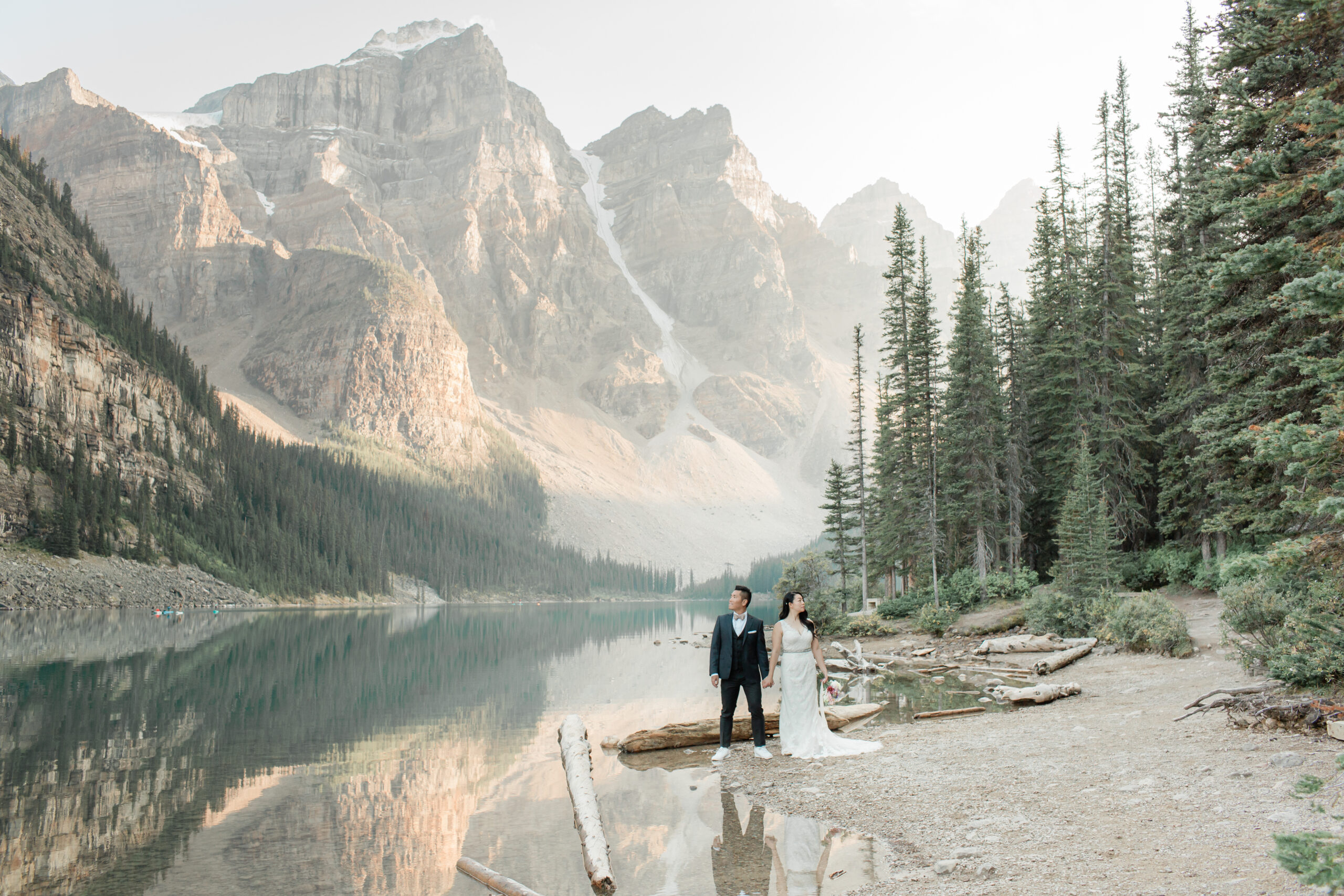 A couple elopes in Banff National Park near an alpine lake.
