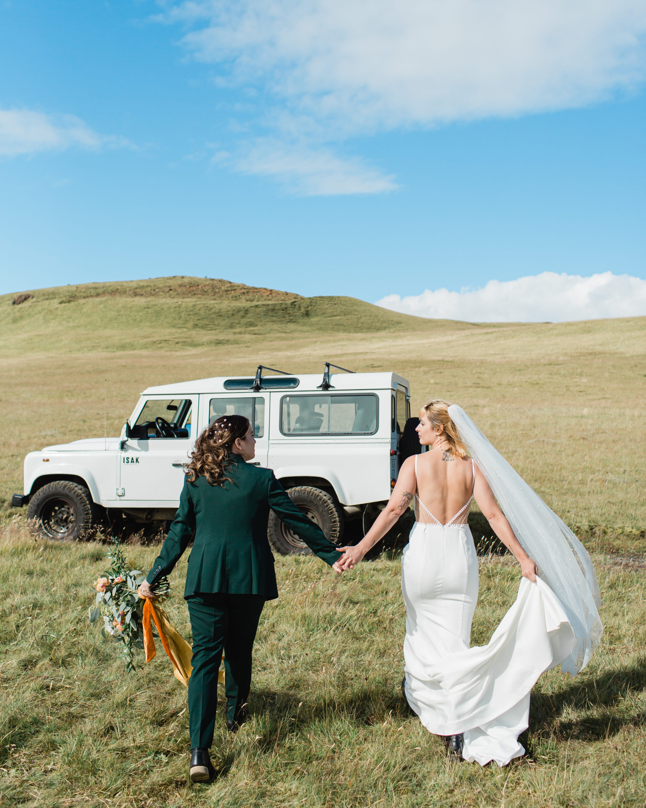 A newlywed couple walks towards their 4x4 vehicle to go off-roading in Iceland.