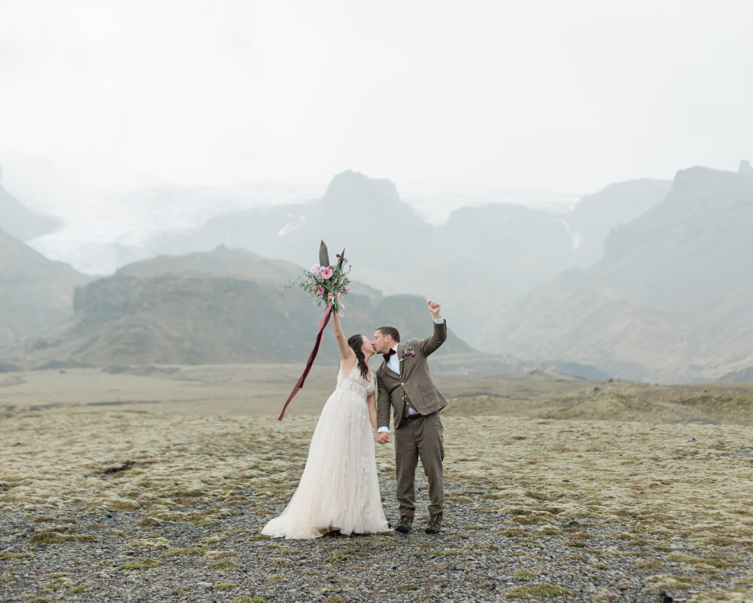 A couple celebrates their wedding ceremony with cheers and a kiss in Iceland.