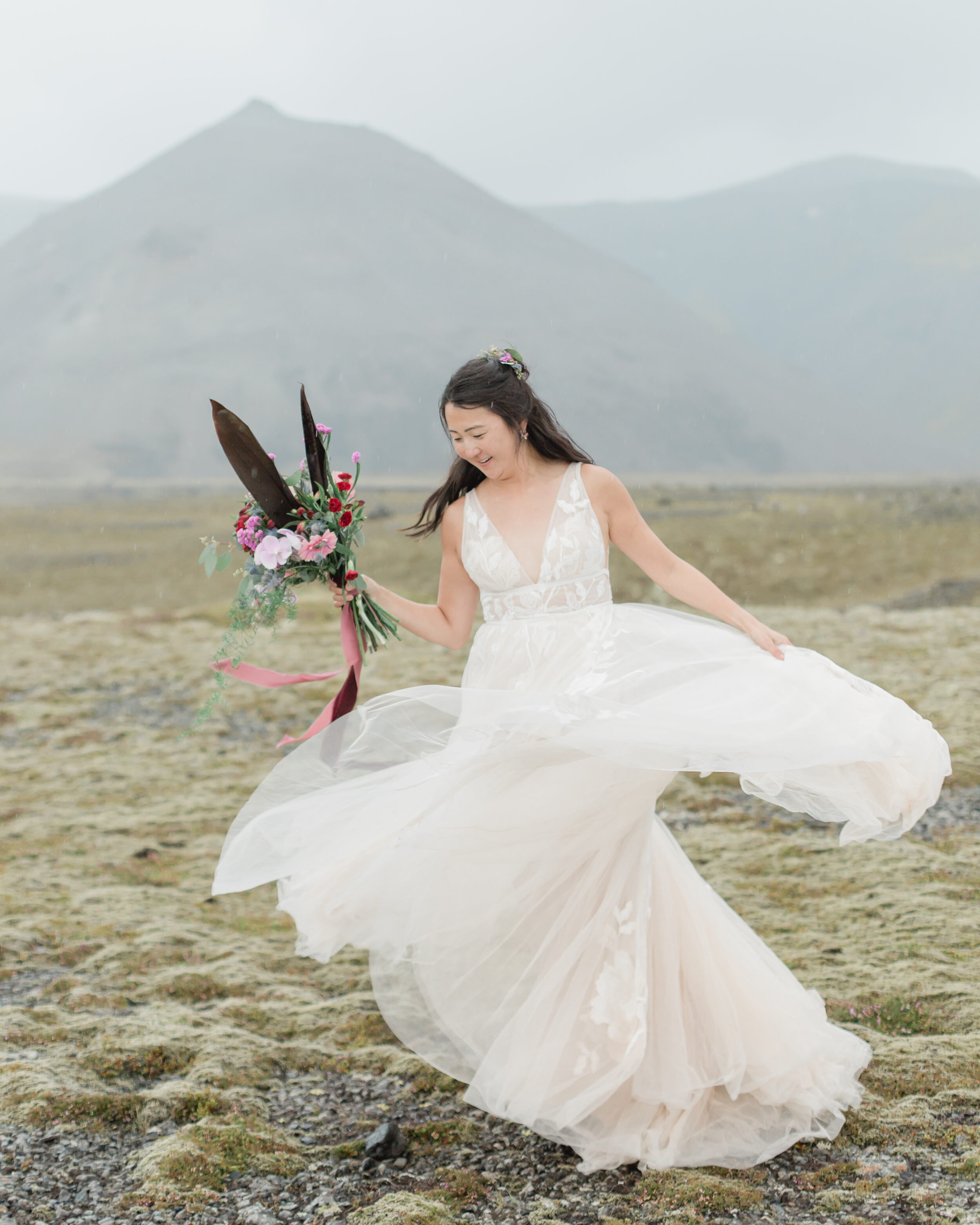 A bride shows off her wedding florals and elopement dress in Icelanad.