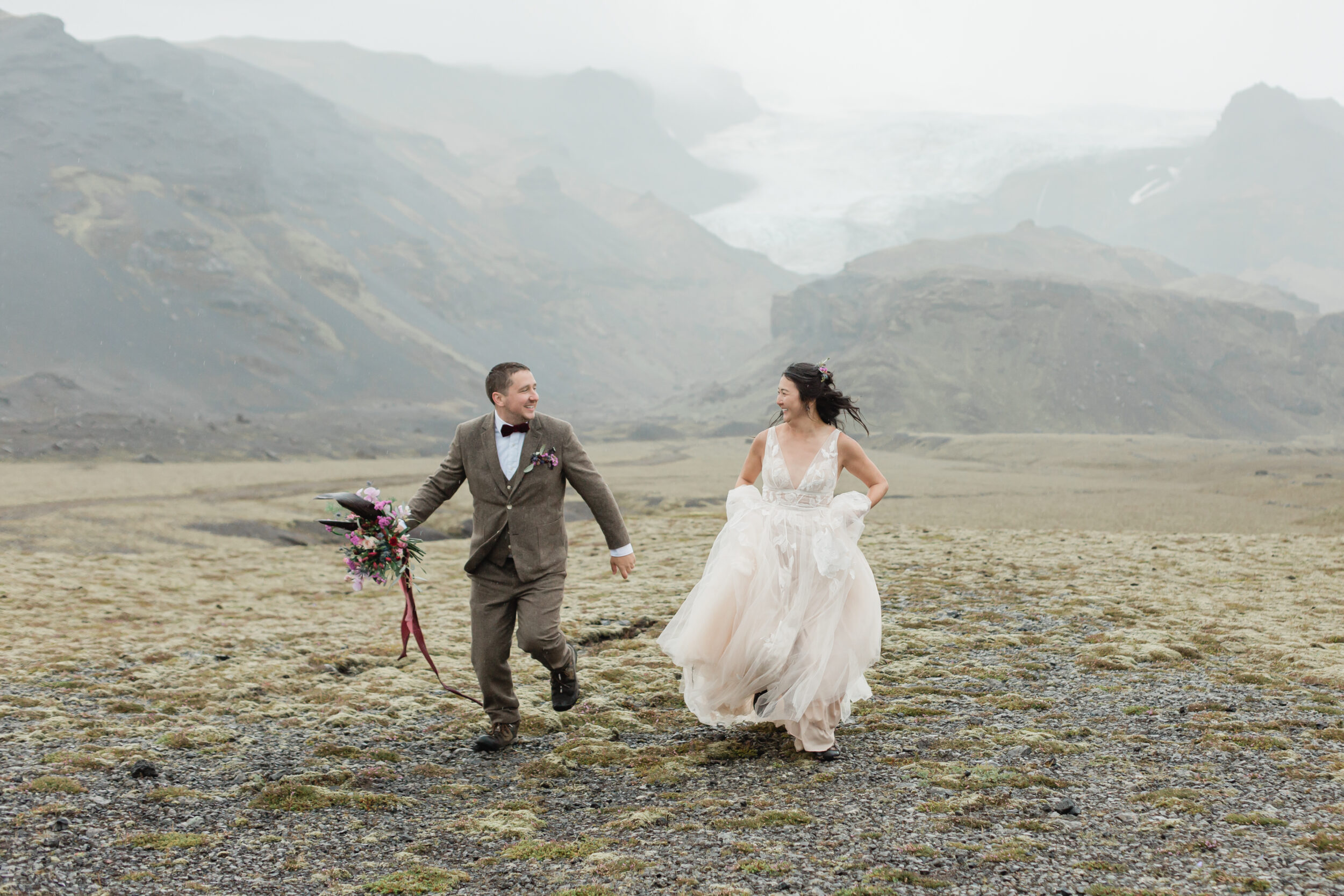 A couple runs through a field in Iceland