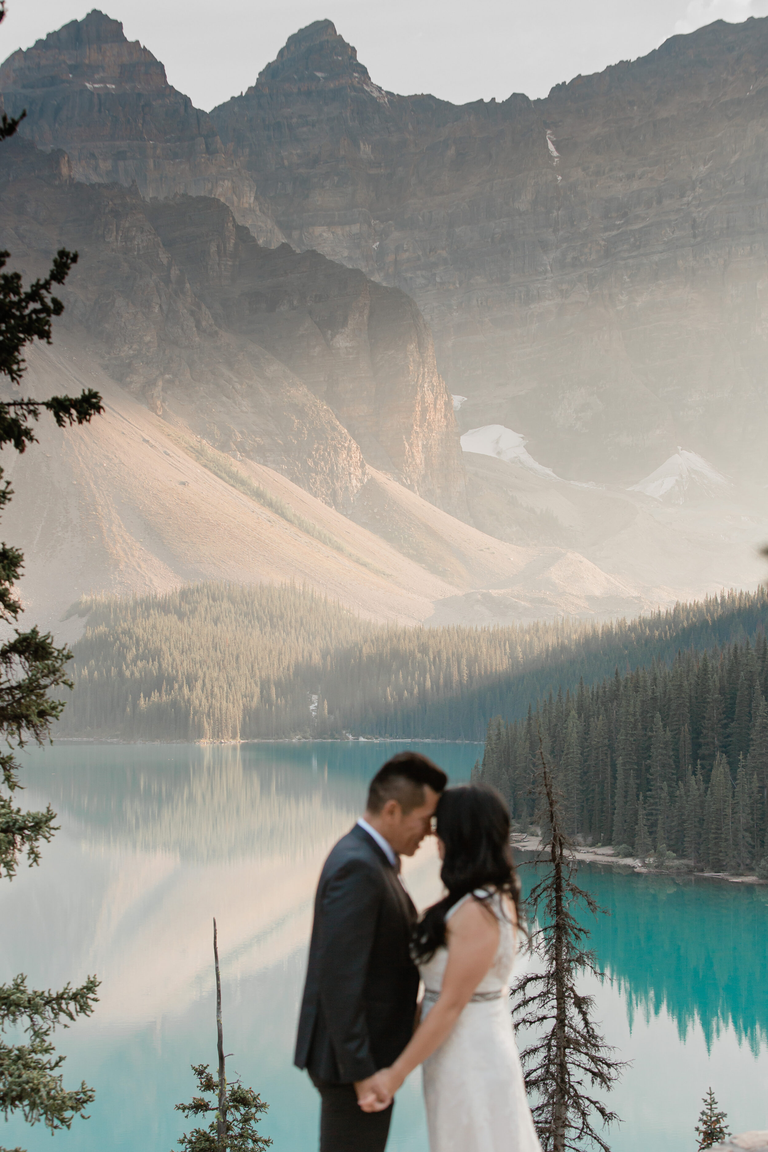 A couple leans in for a kiss while on an overlook in Banff National Park.