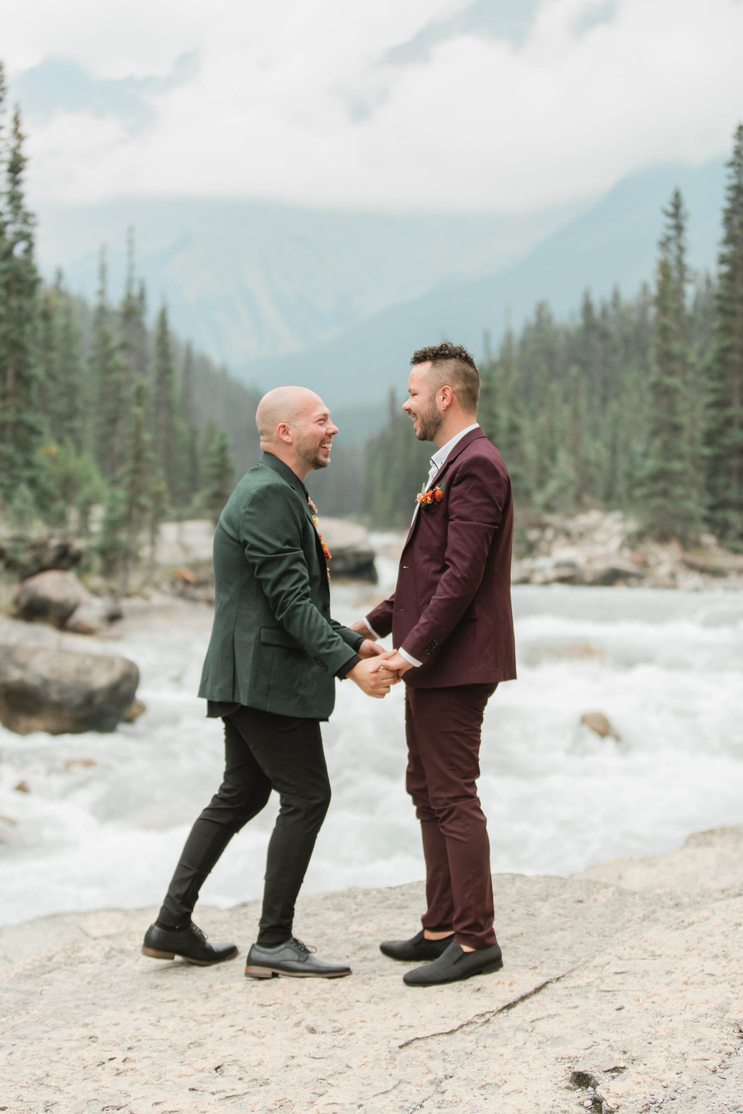 A couple exchanges vows along a flowing river in Banff National Park.