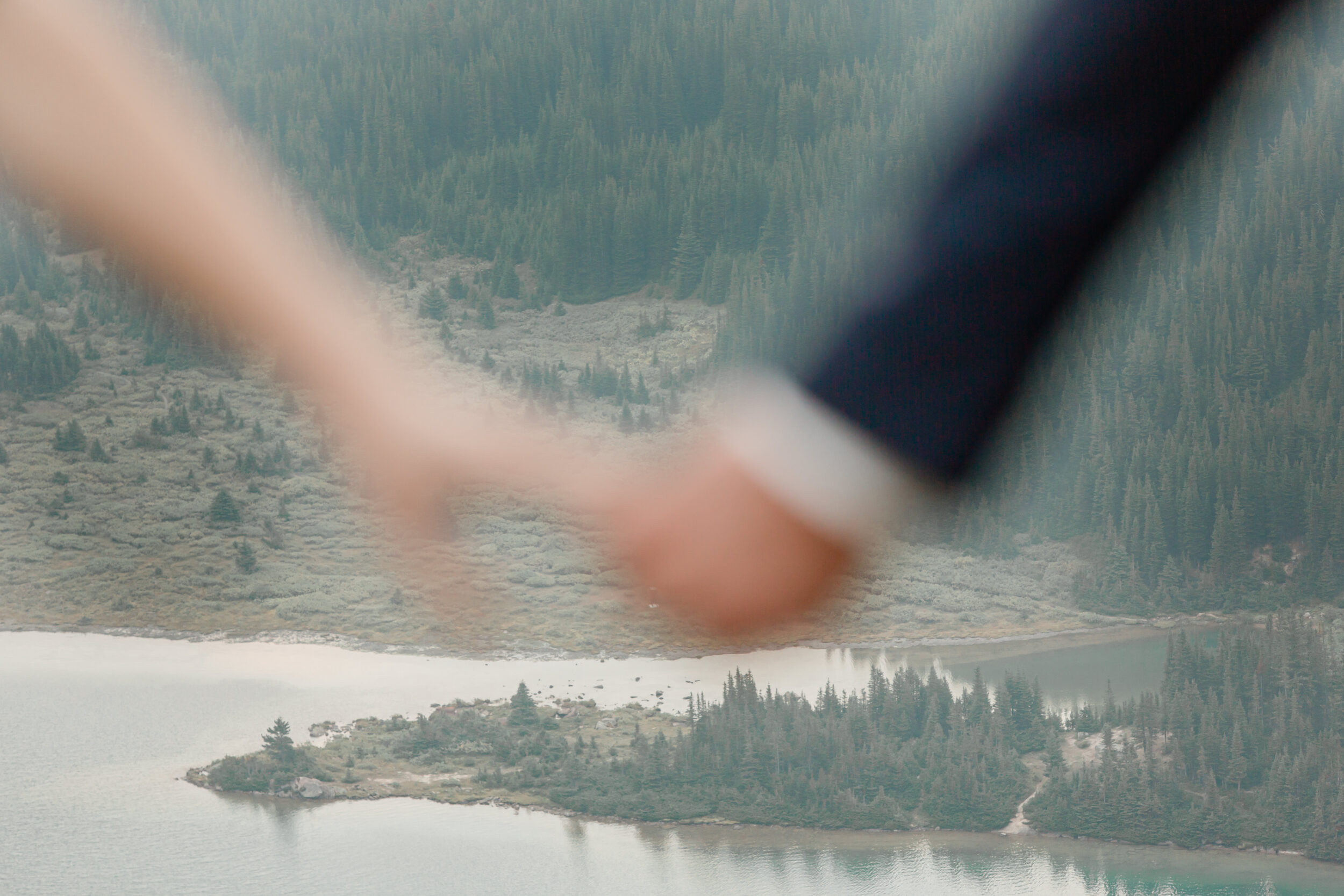 A couple holding hands with an alpine lake in the background.
