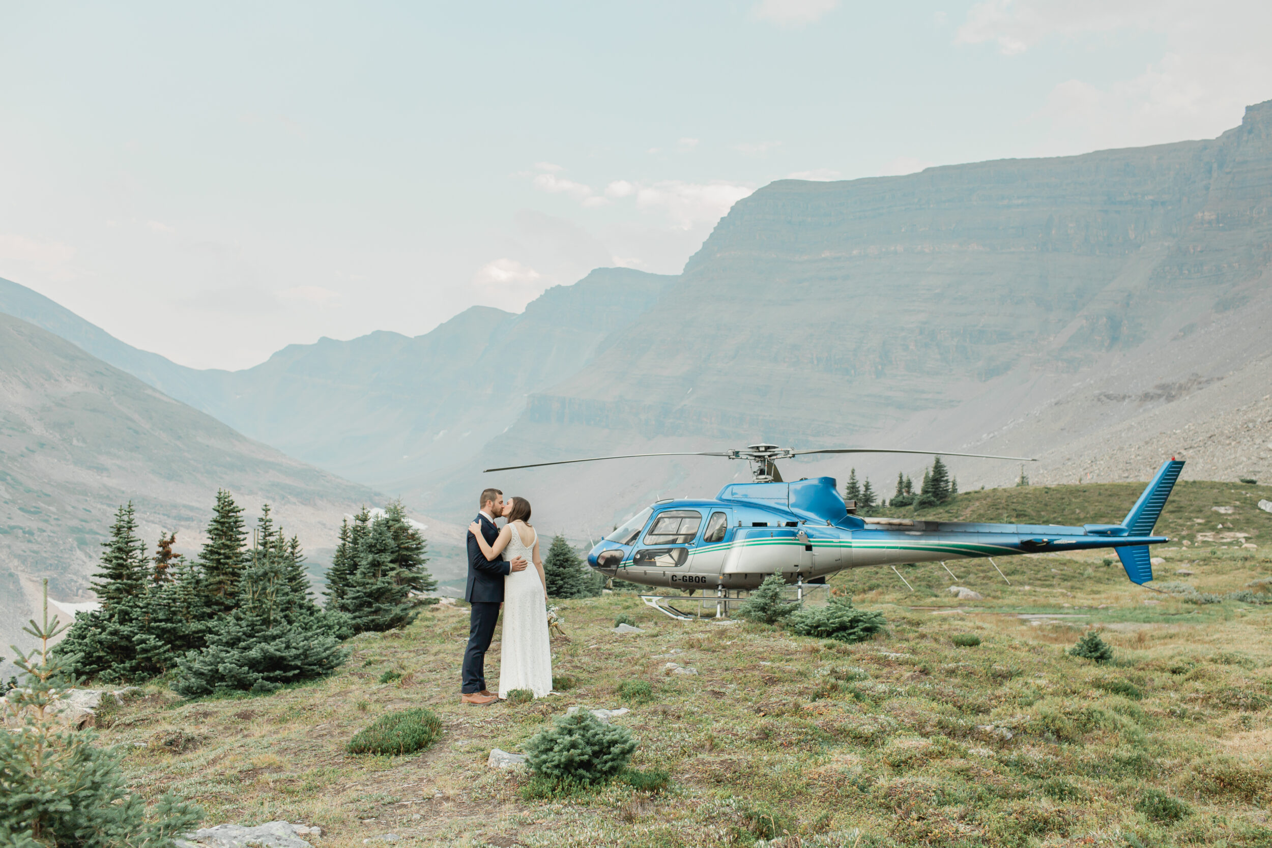 A couple shares a kiss before flying off to their heli elopement in Banff.