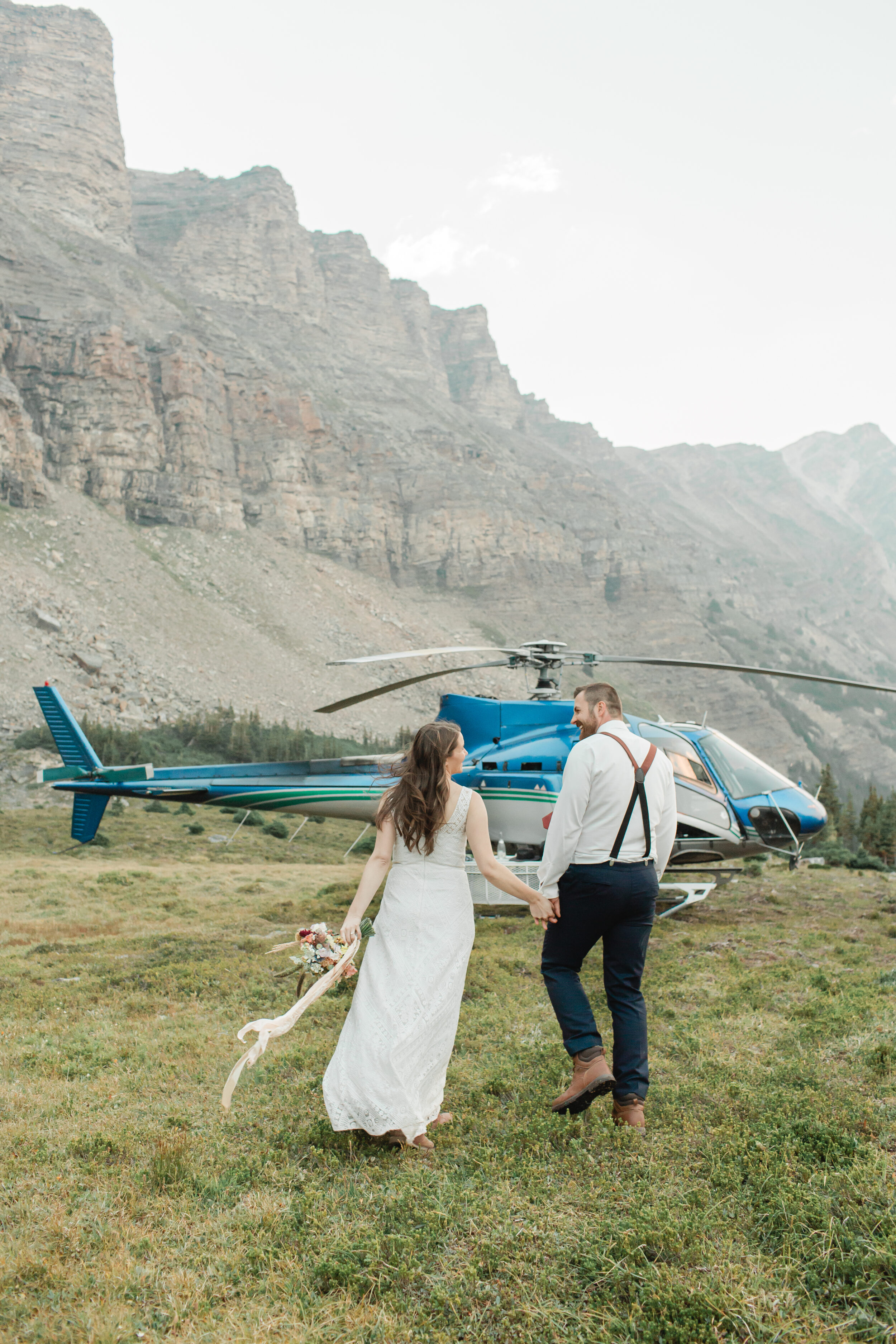 A couple walks towards a helicopter for their Banff elopement.