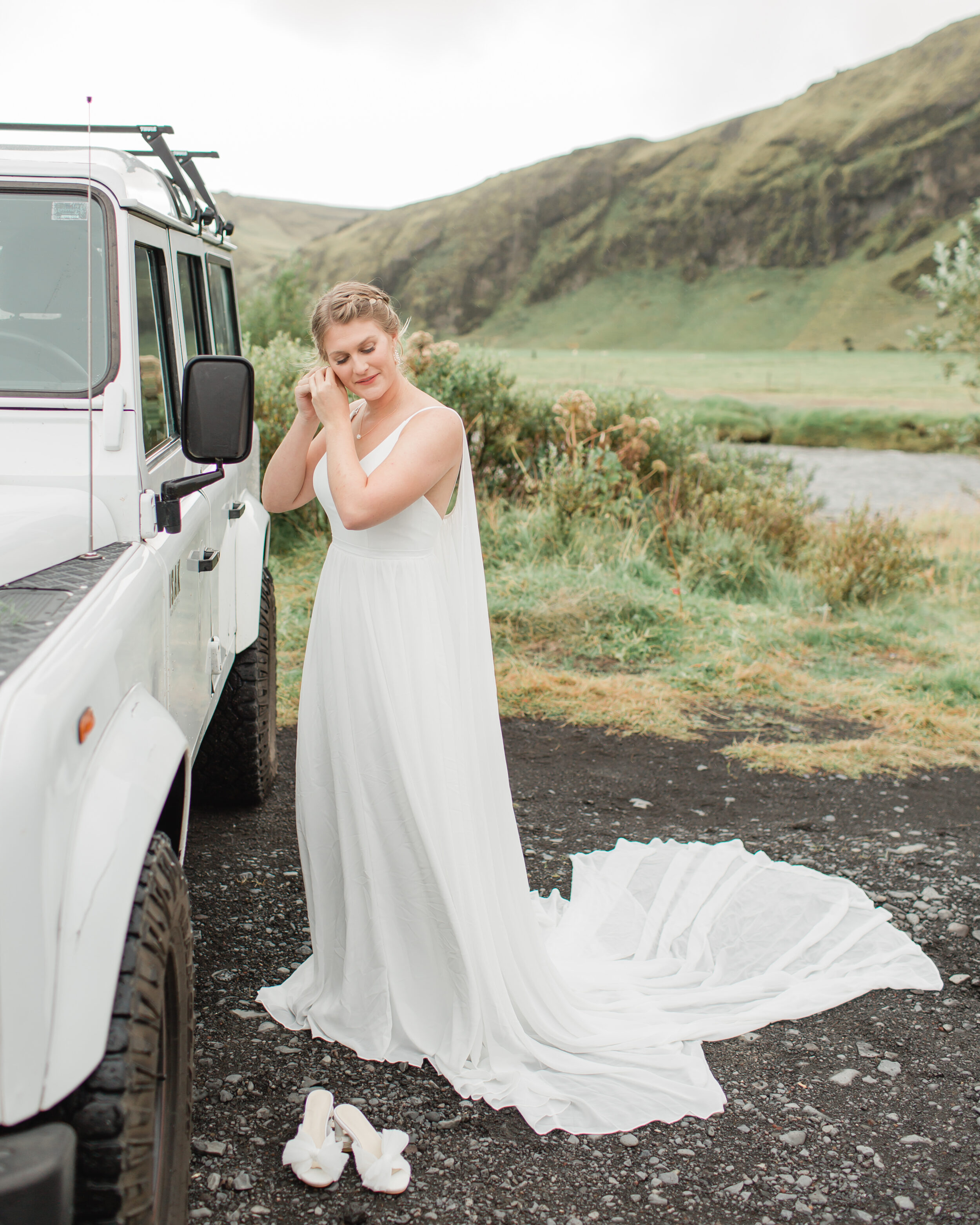 A bride get's reading for her Skogafoss elopement near a 4x4 vehicle in Iceland.