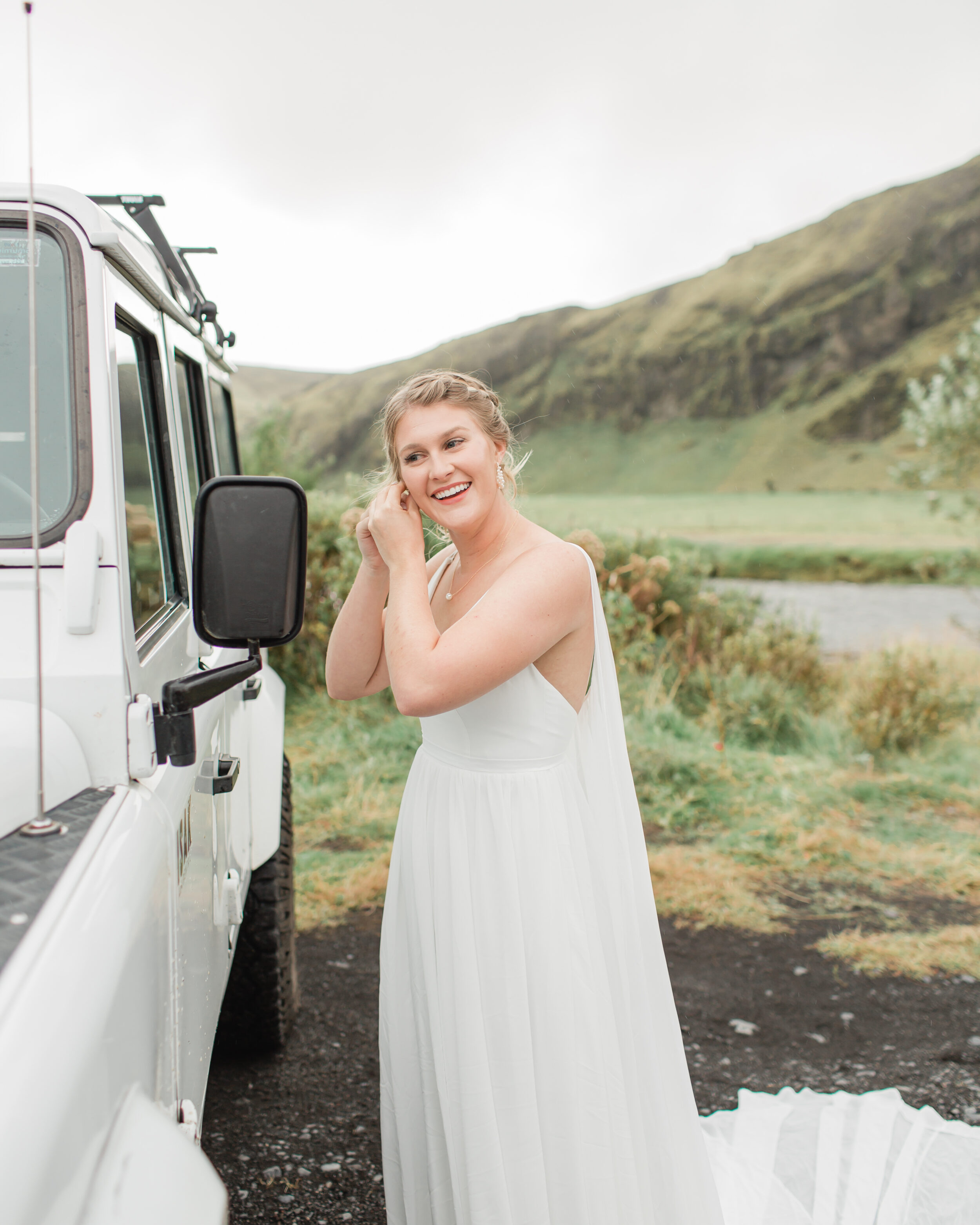 A bride puts on earrings in the mirror of a Defender in Iceland. 