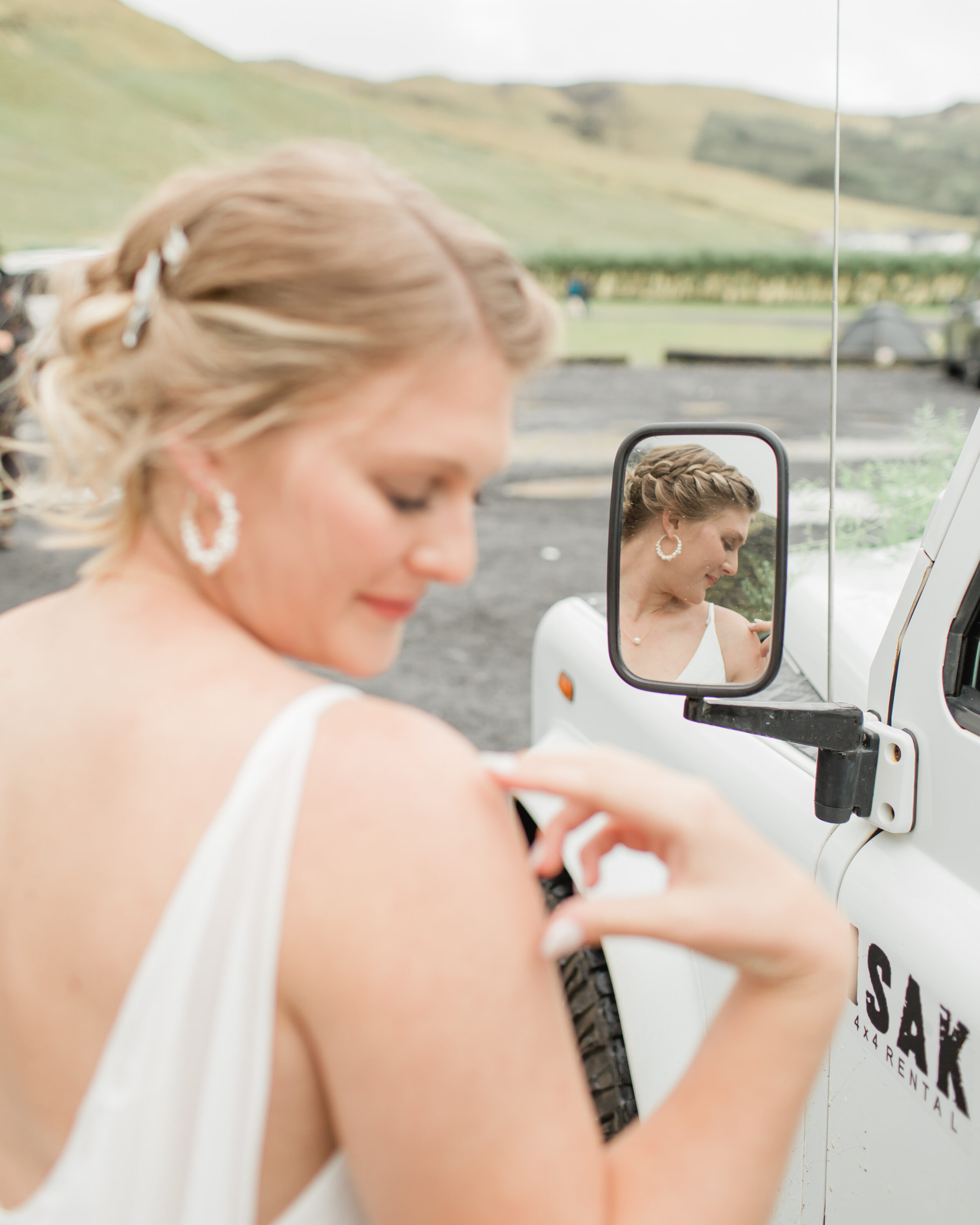 A bride looks at her shoulder while standing near a 4x4 vehicle in Iceland.