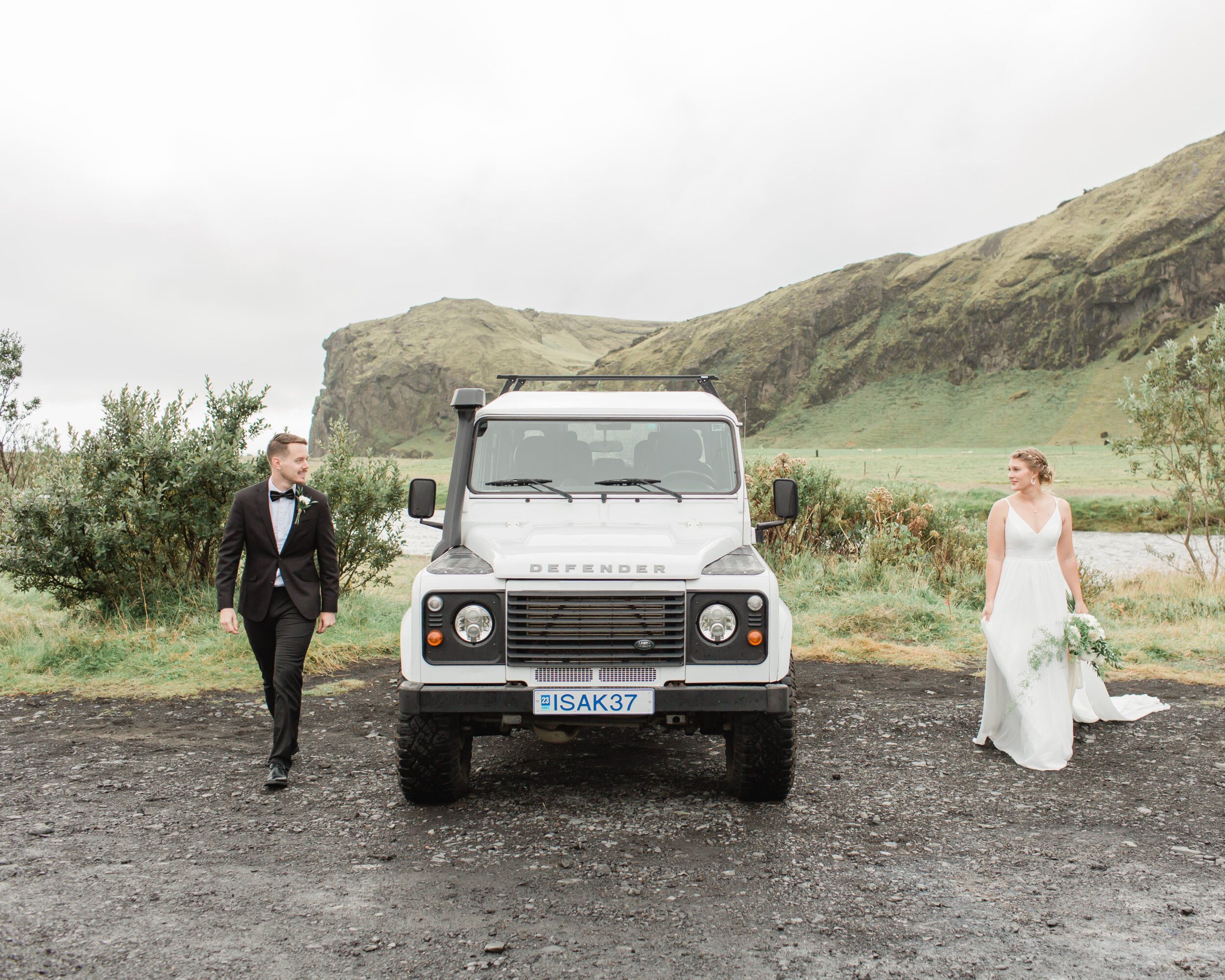 A Defender is parked between a man and woman before their first look for their Iceland elopement. 