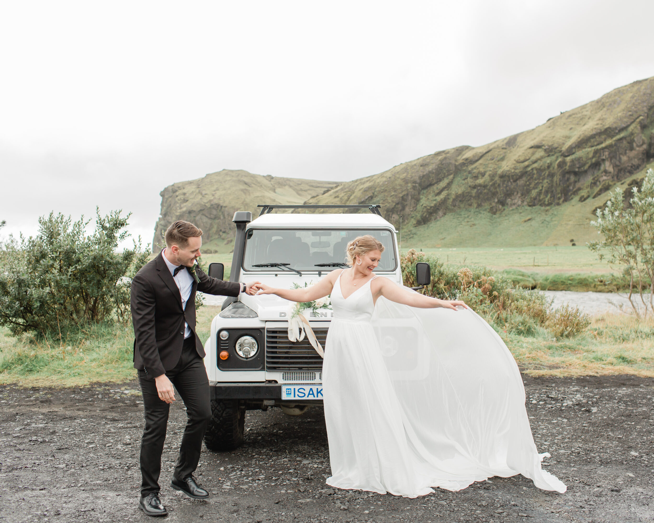A groom spins his wife in admiration while standing near an Icelandic stream. 