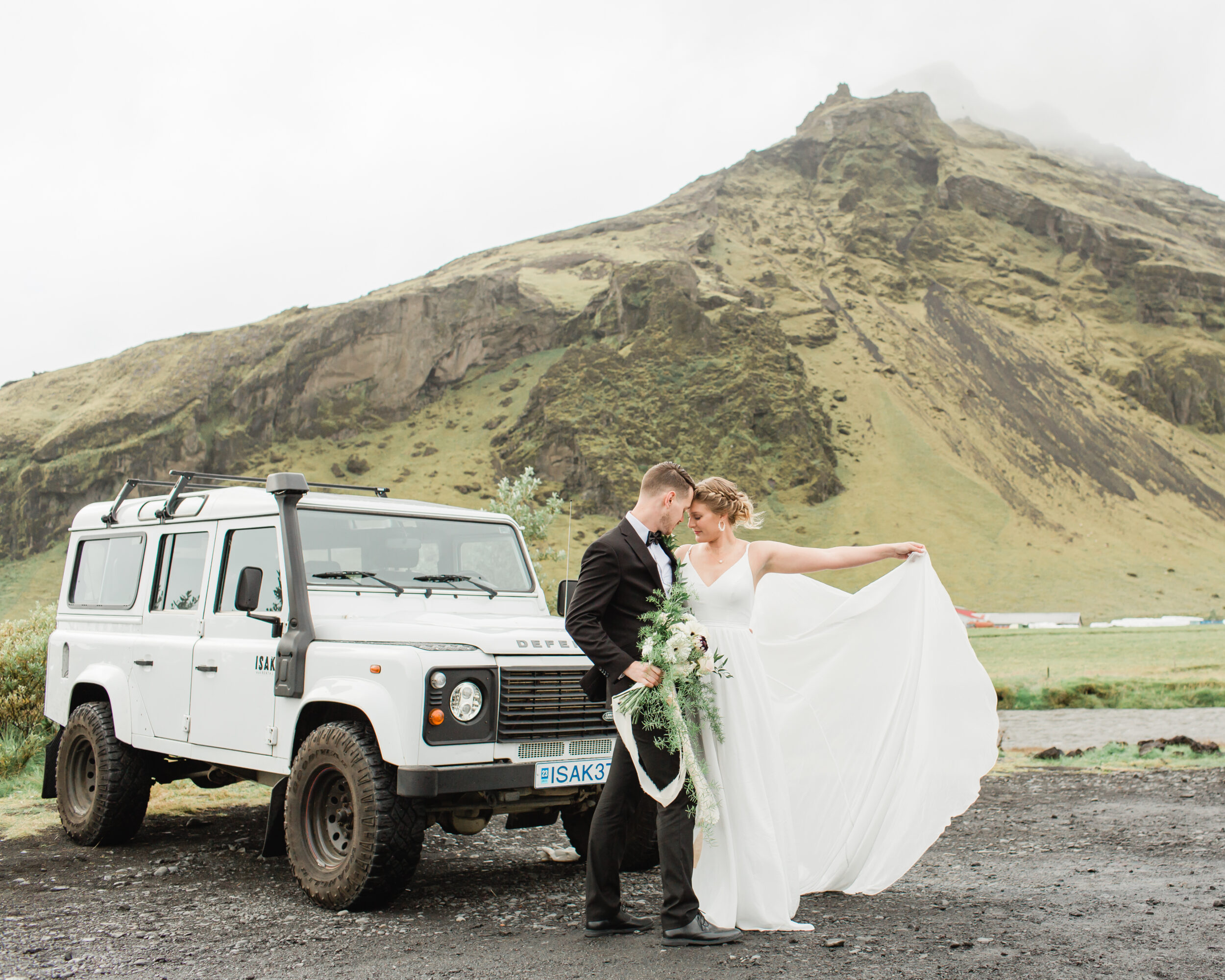 A bride shows off her white wedding dress before here Skogafoss elopement vows. 