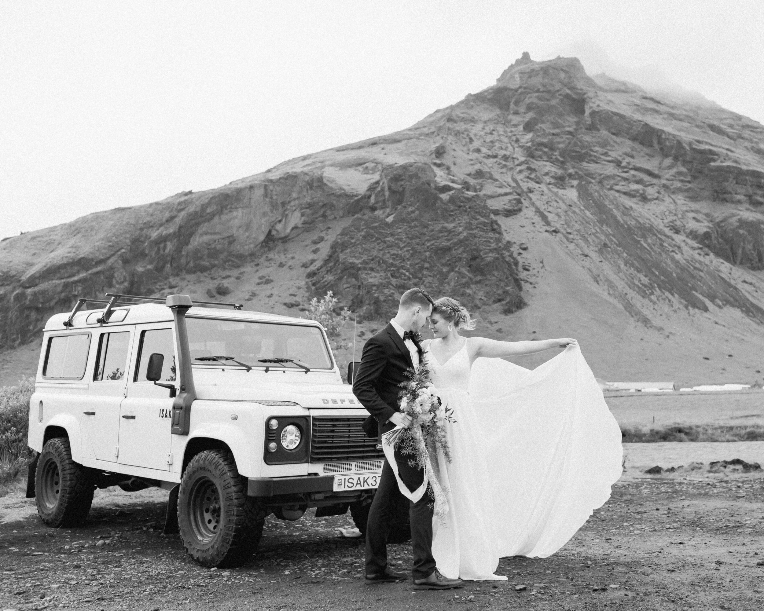 A couple poses in front of a Defender while celebrating their Iceland elopement.