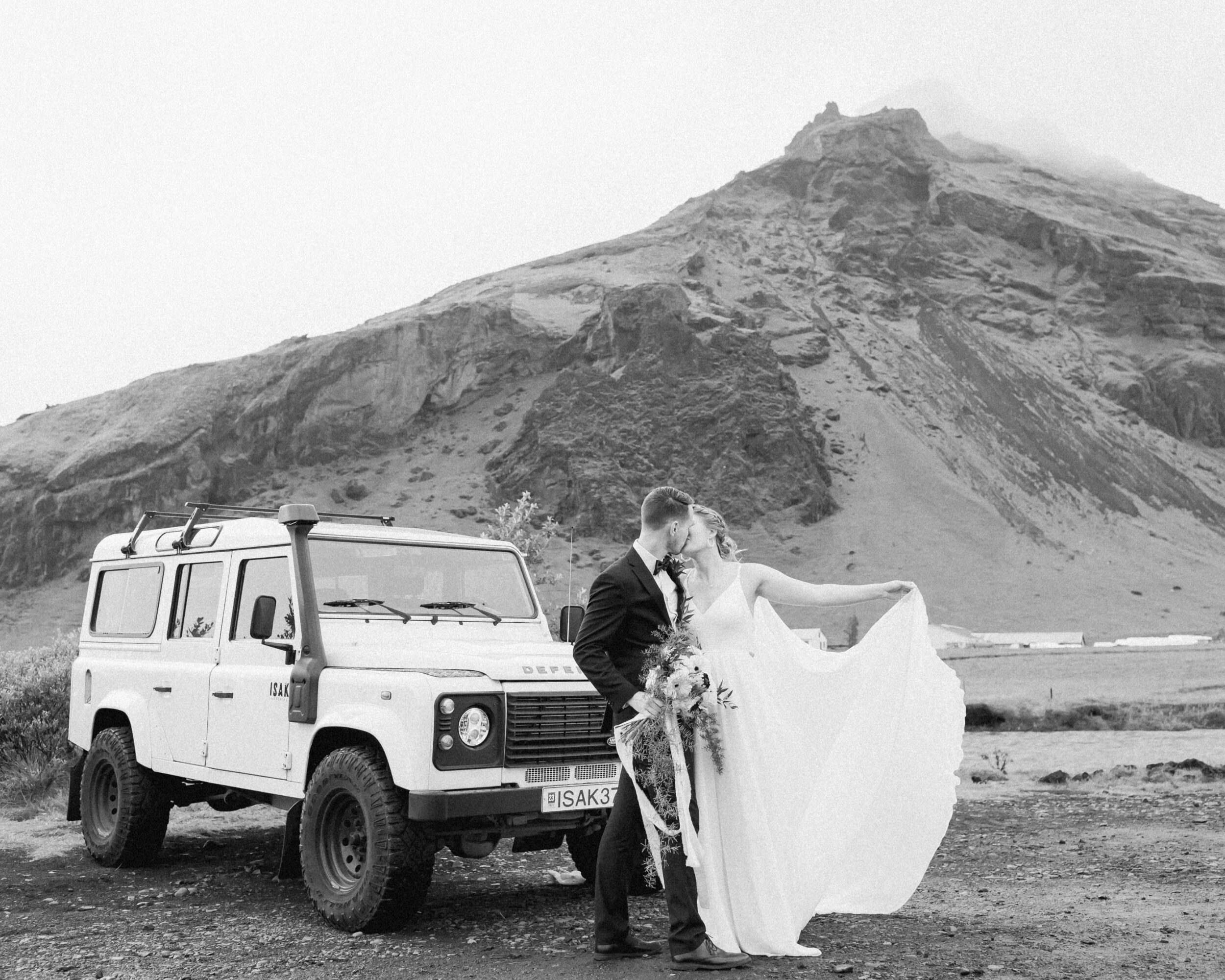 A couple kisses beneath a mountain in Iceland before their intimate wedding.