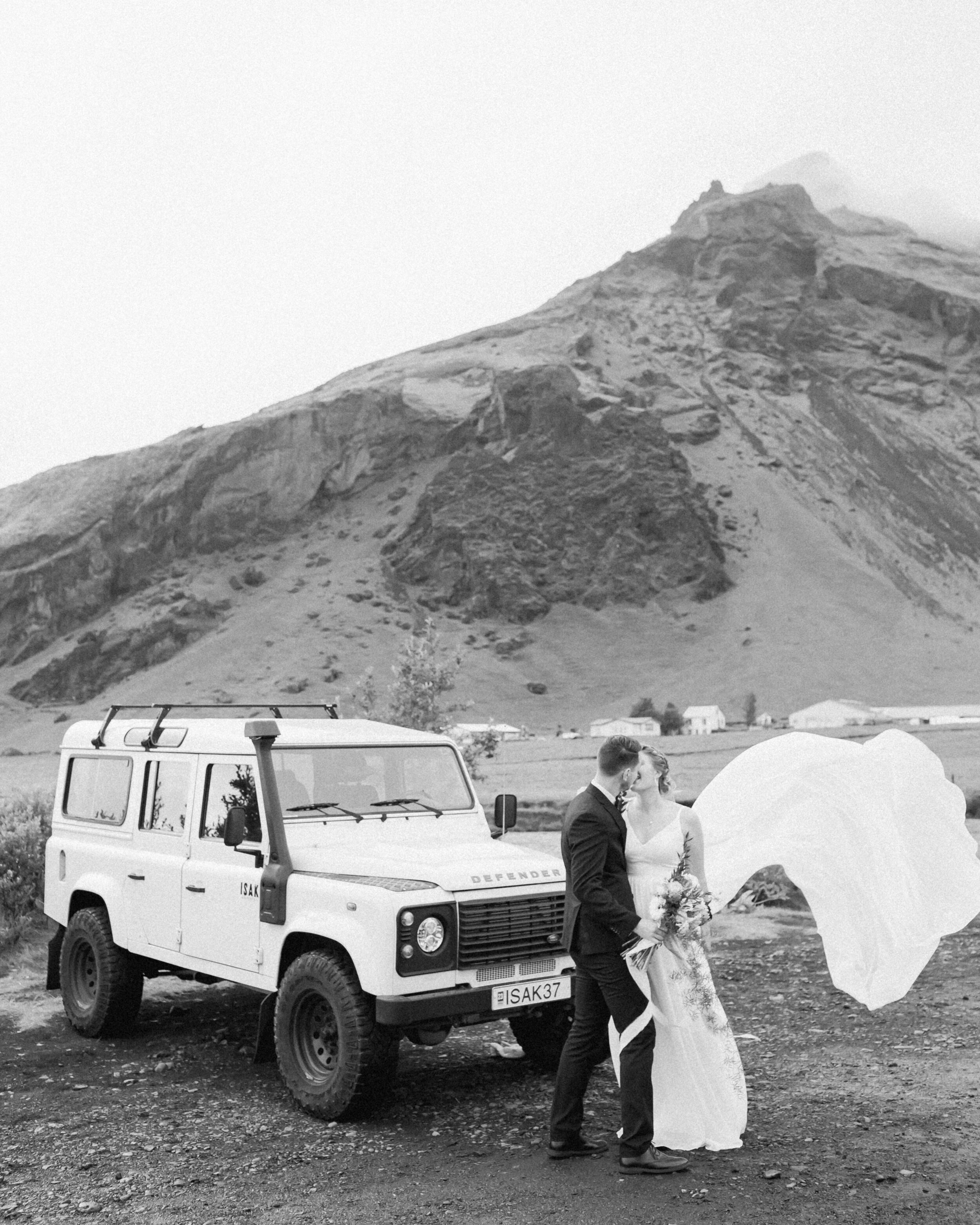 A Defender is seen near Skogafoss with a couple standing in front of it before their elopement. 