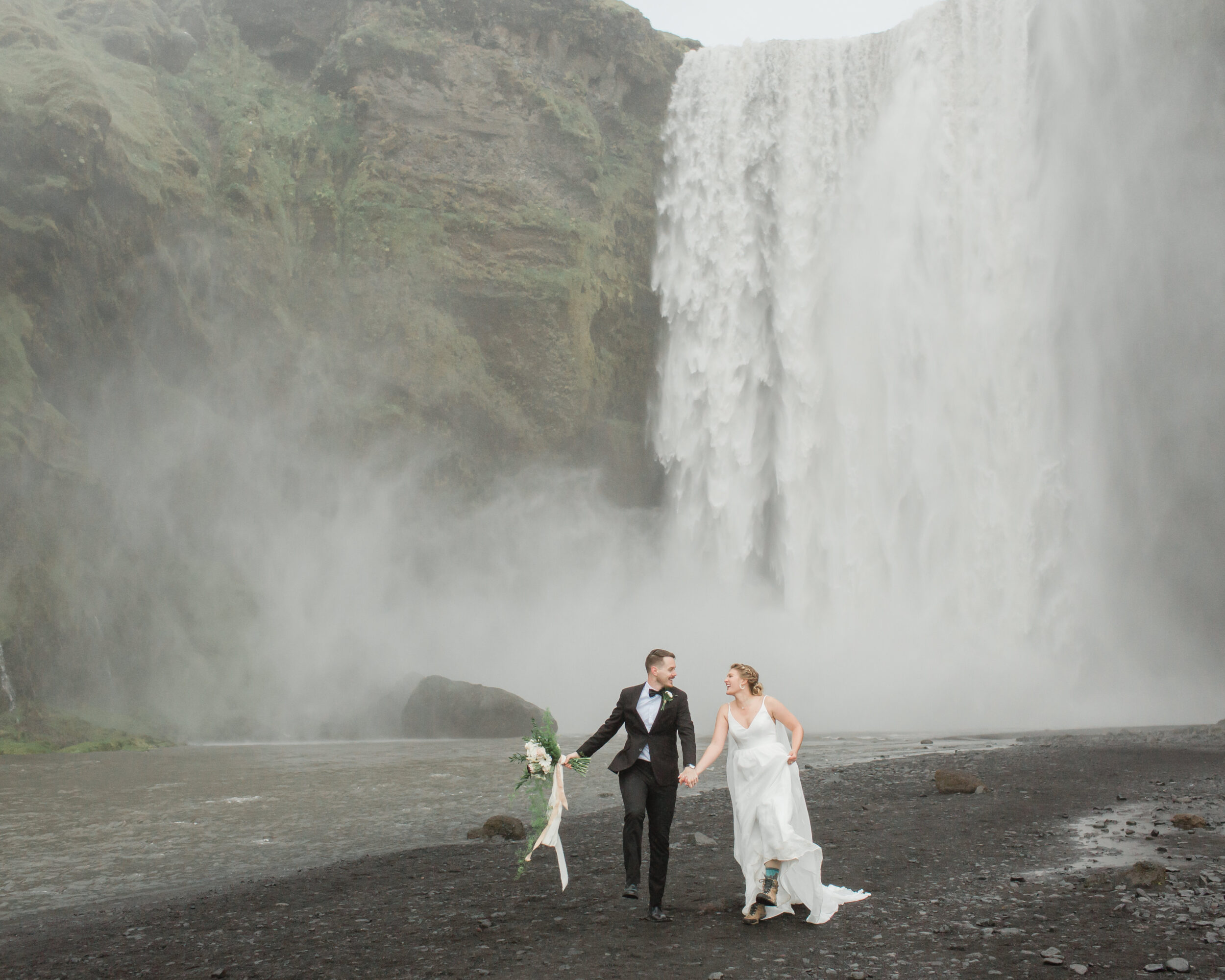 Newlyweds celebrate their coastal elopement at Skogafoss in Iceland. 