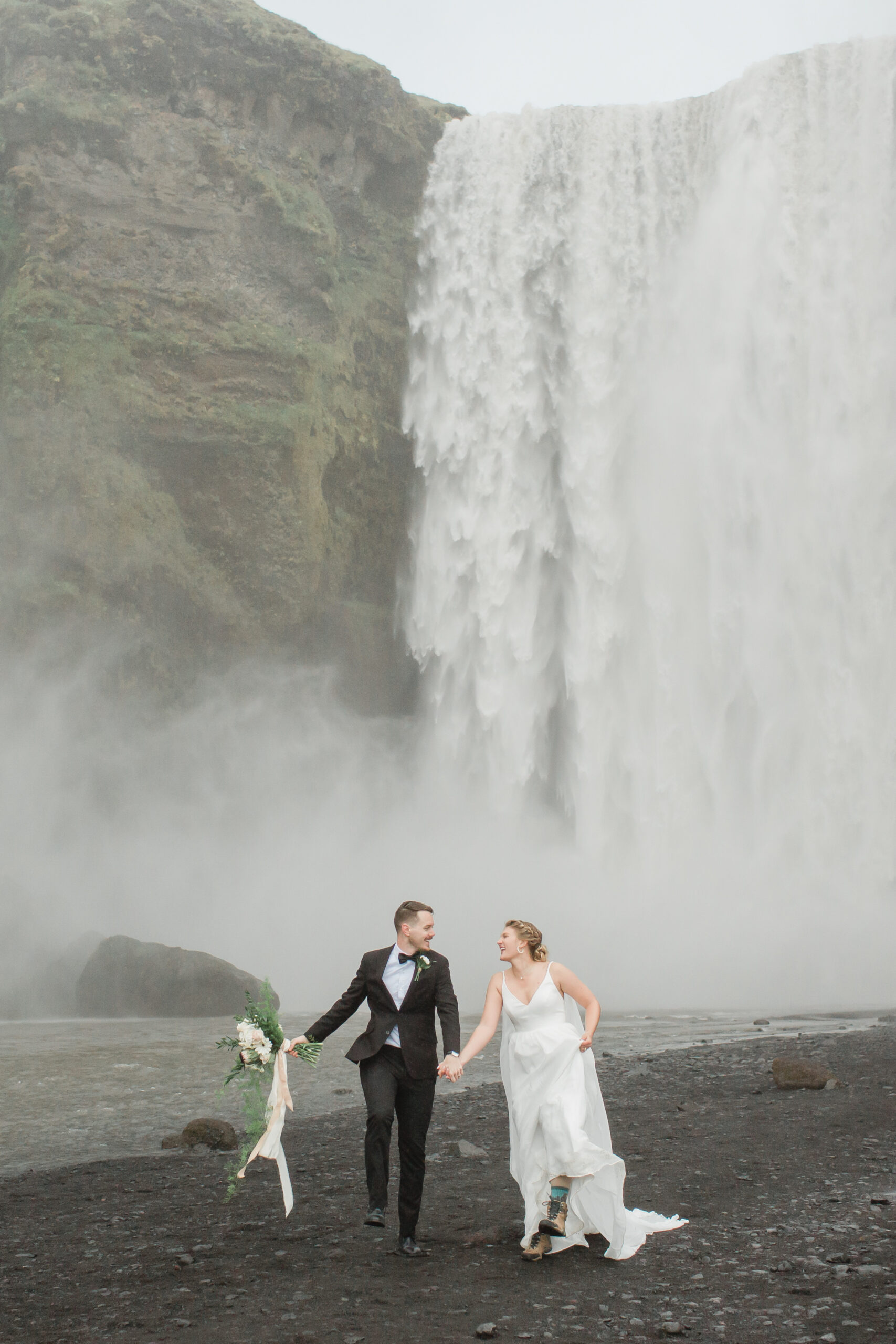 A beautiful couple is seen skipping near Skogafoss during their Iceland elopment.
