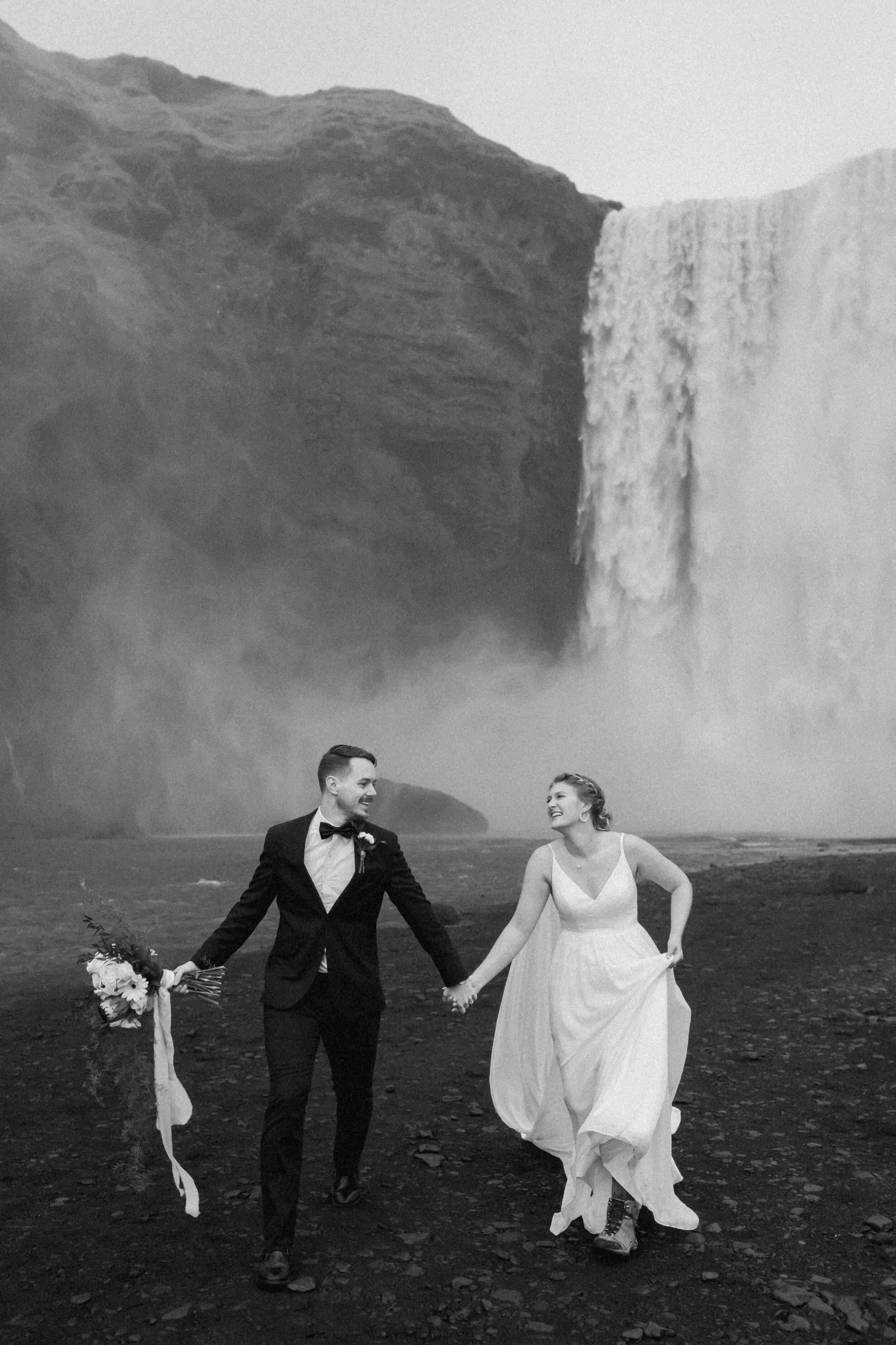 A couple holds hands while celebrating their Skogafoss elopement. 