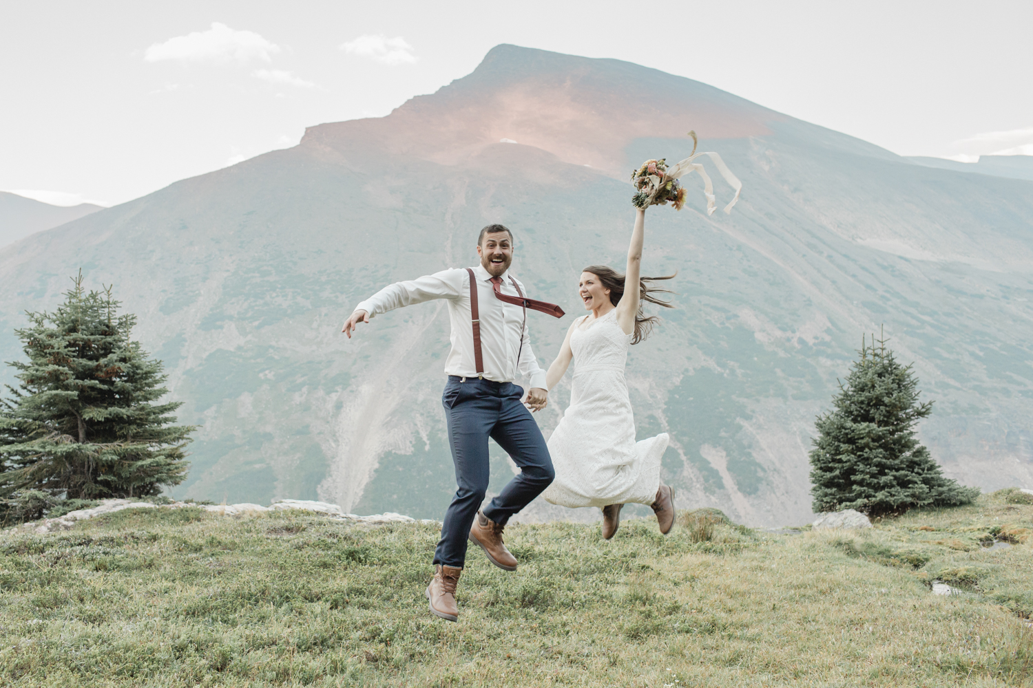 couple jumping in excitement after their wedding at the top of a mountain near banff national park