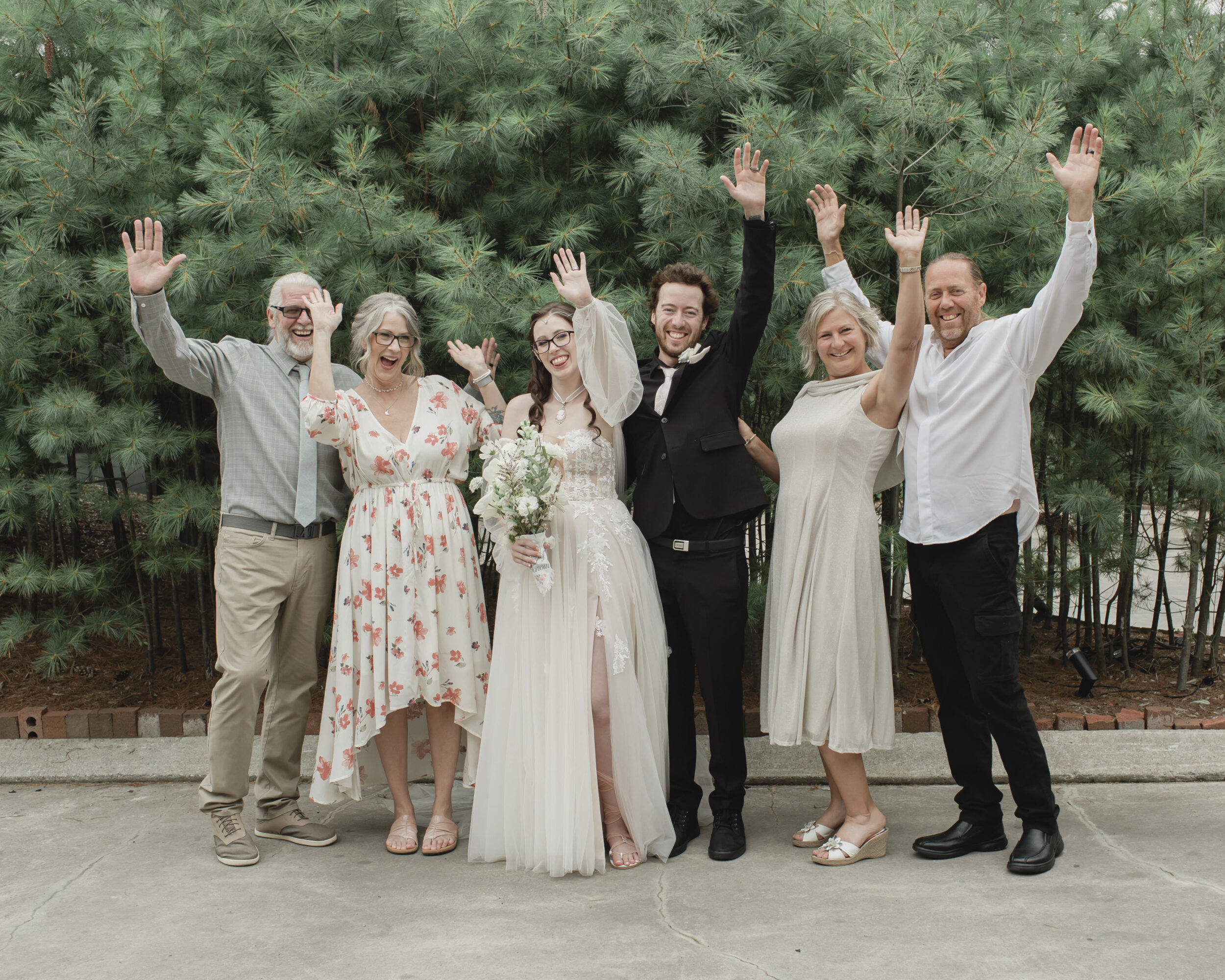 A bride, groom and their wedding guests pose and wave. 