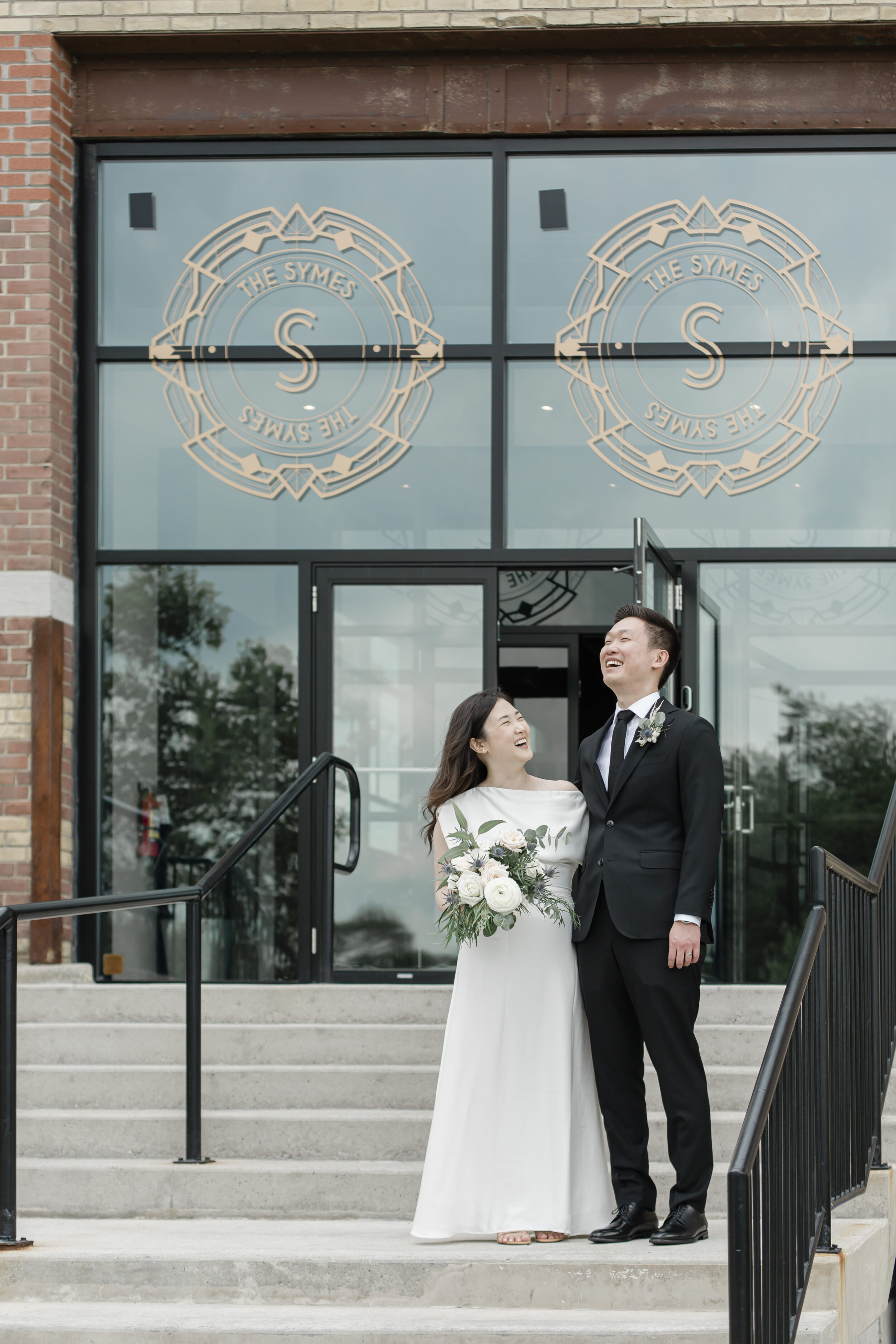 A couple shares a laugh on the stairs of a building in downtown Toronto while taking wedding portraits. 