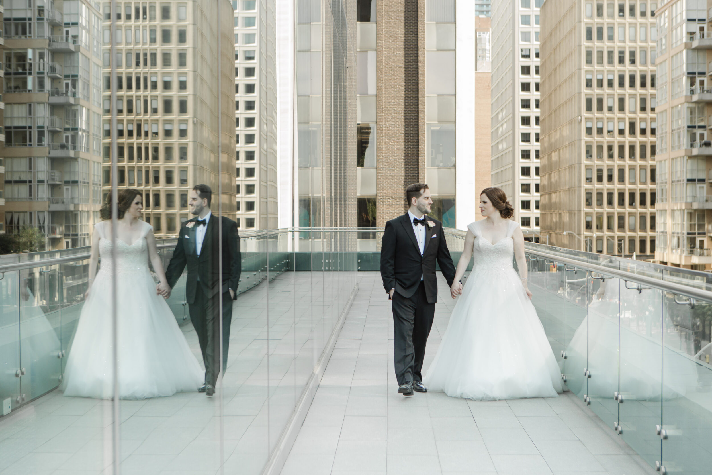 A couple walks along a glass railing after their Toronto wedding. 