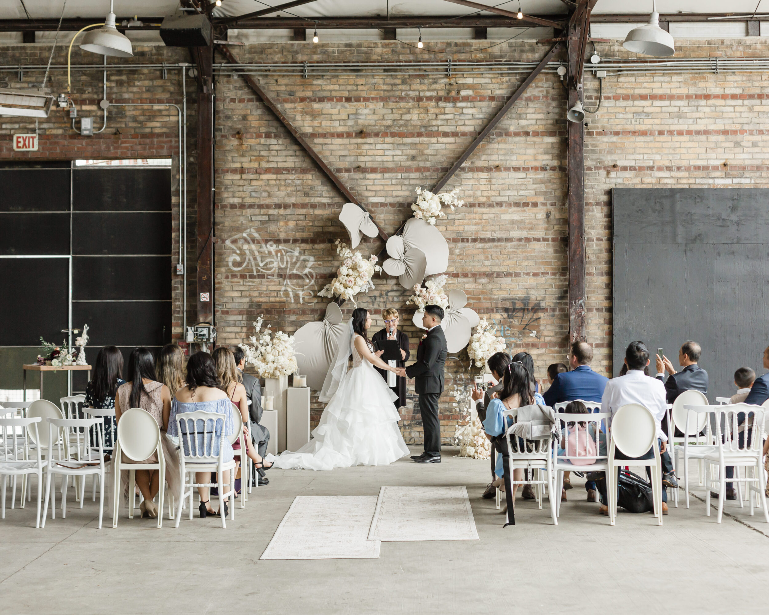 A couple holds hands while saying vows at Evergreen Brickworks in Toronto. 