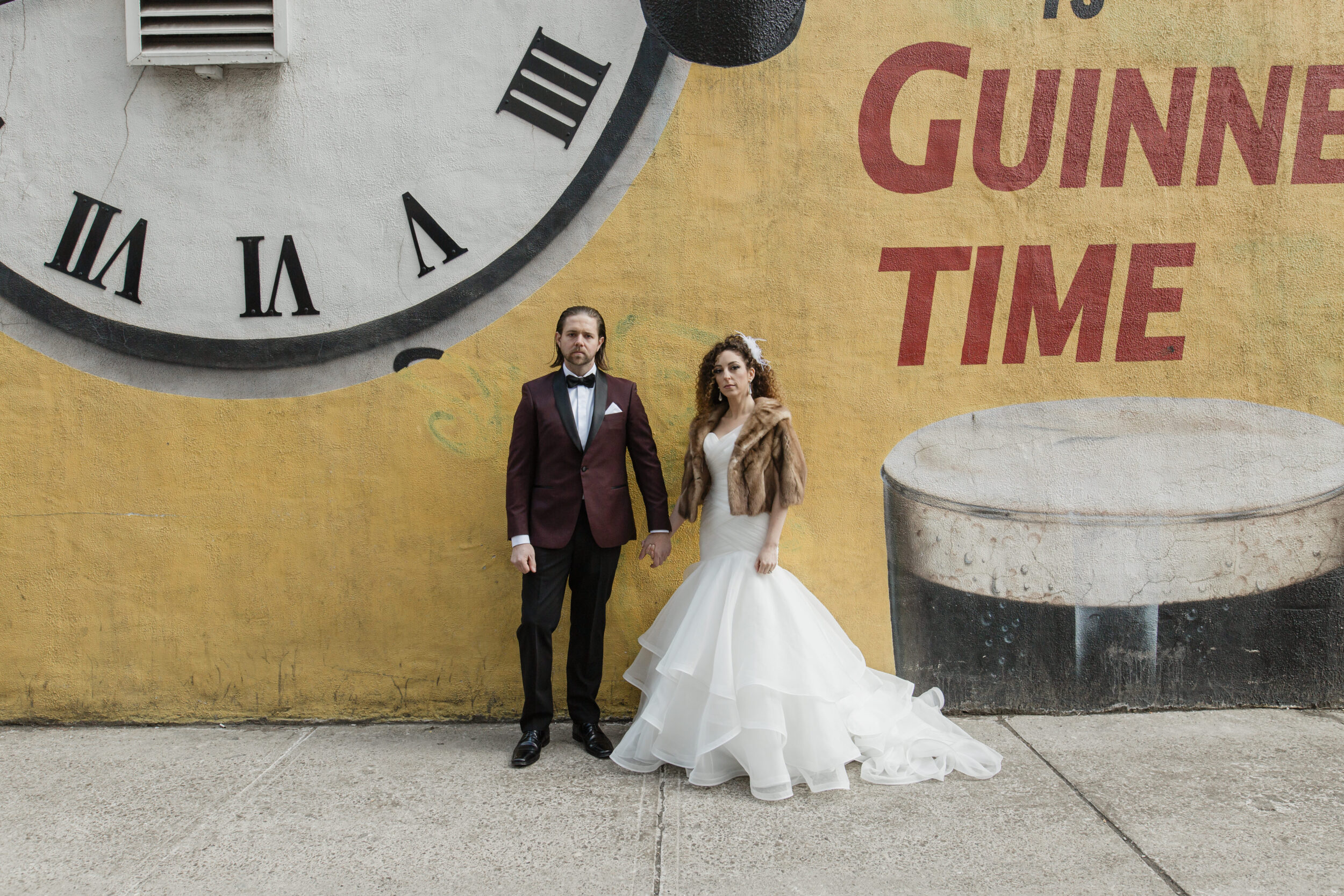 A couple stands in front of a mural in Toronto during their wedding portraits. 