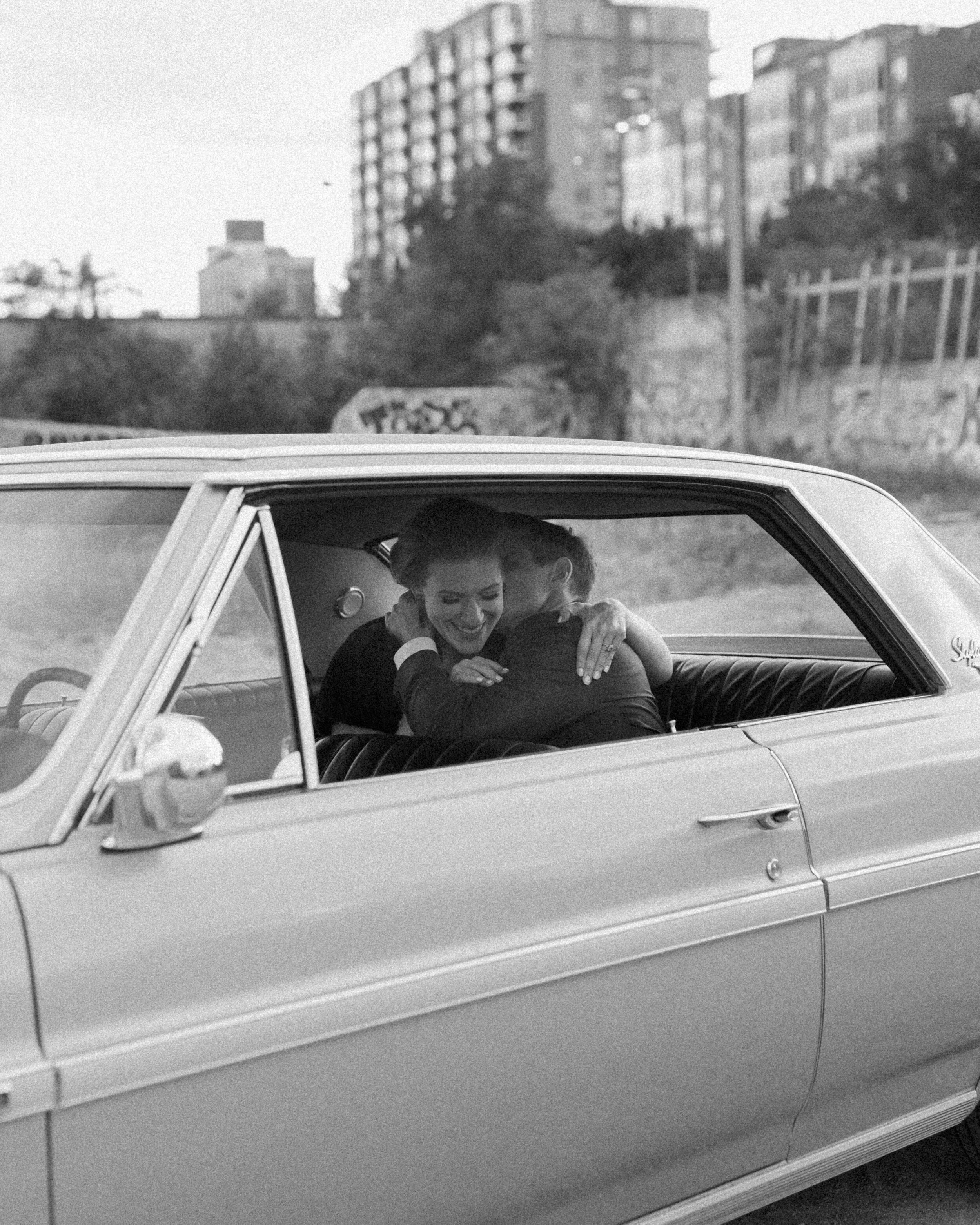 A couple kisses in a car in an urban area of Toronto.