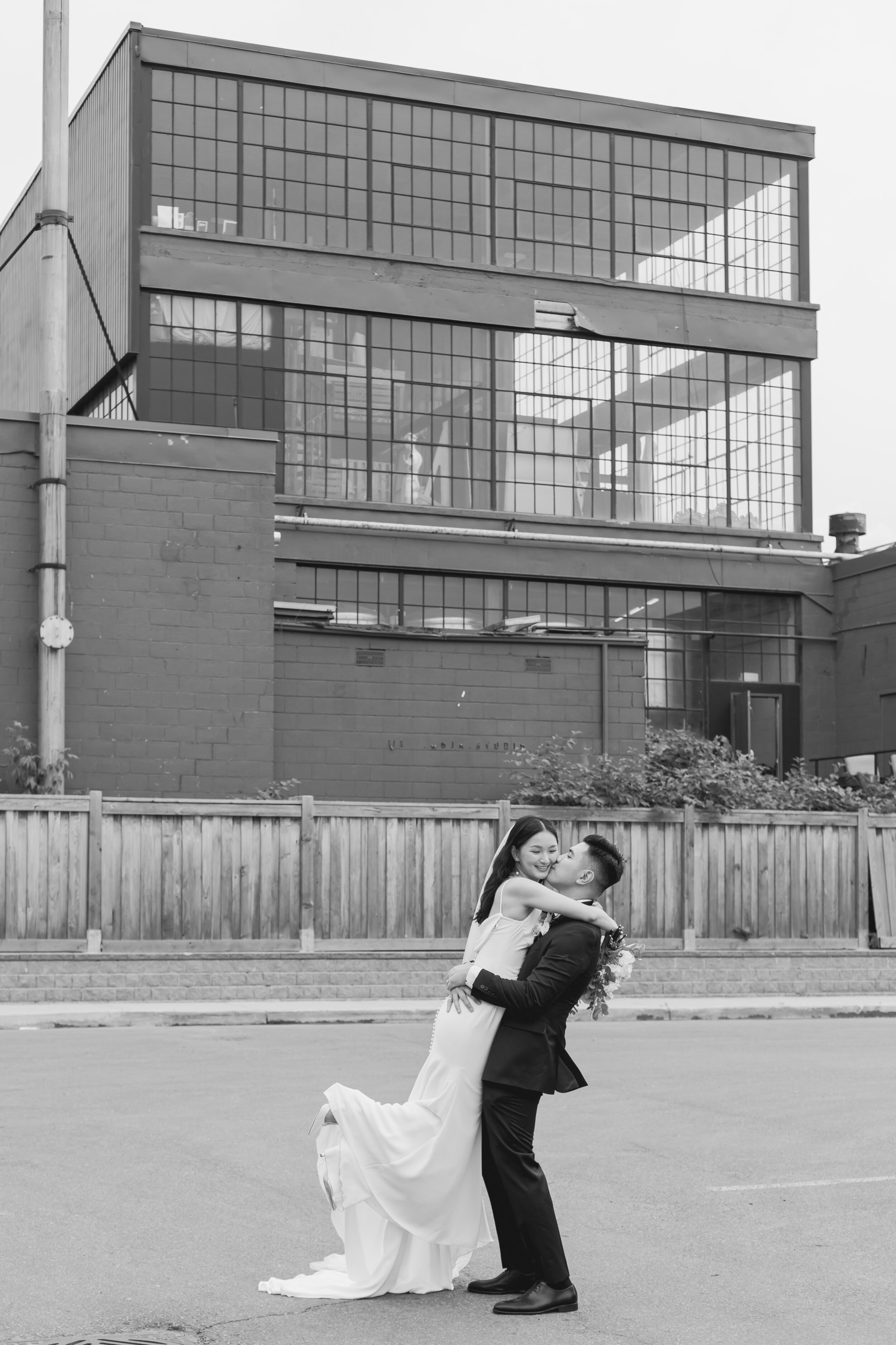 A couple celebrates their elopement in the streets of Toronto near a historic brick building.