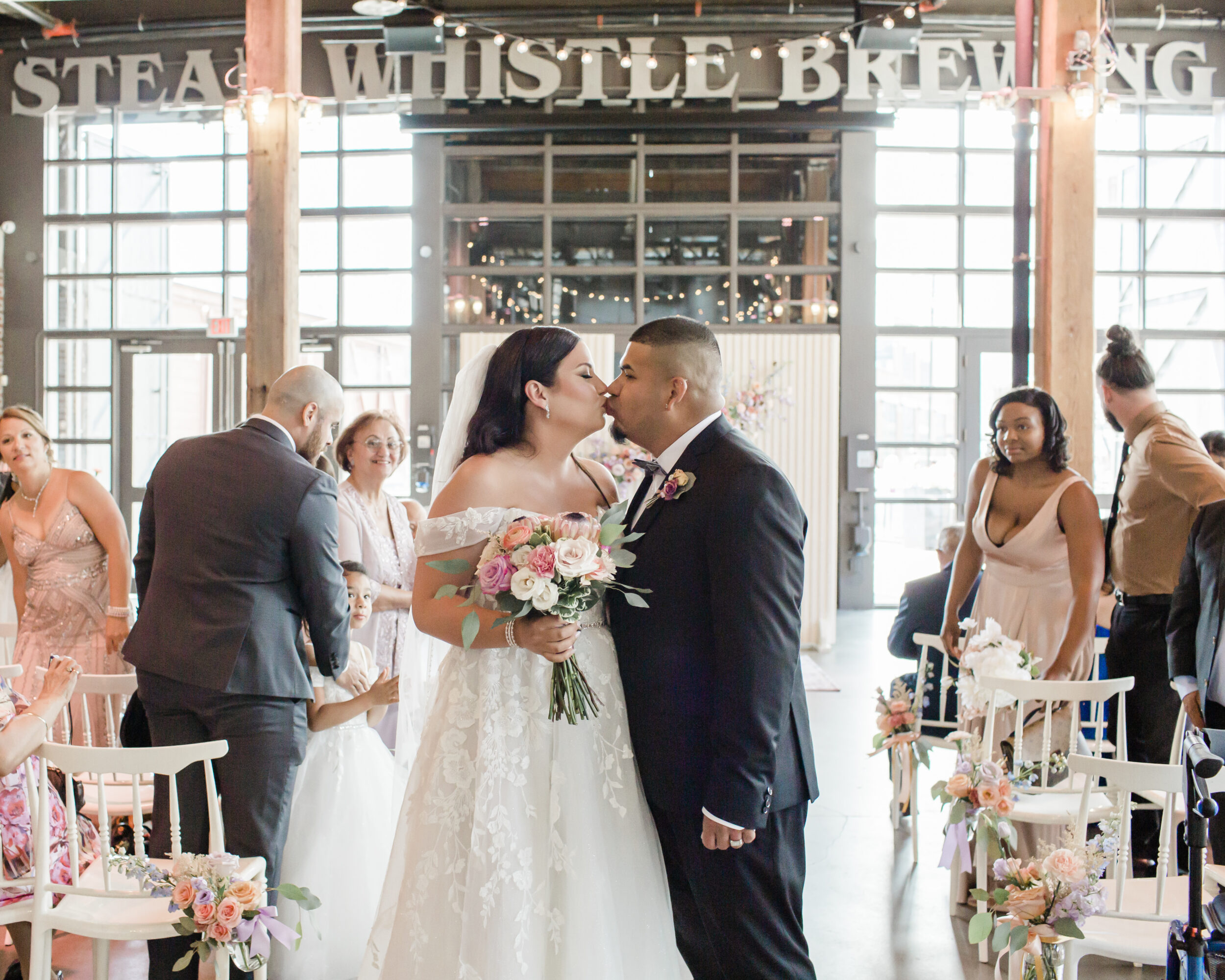 A couple kisses during their wedding ceremony at Steam Whistle Brewery.