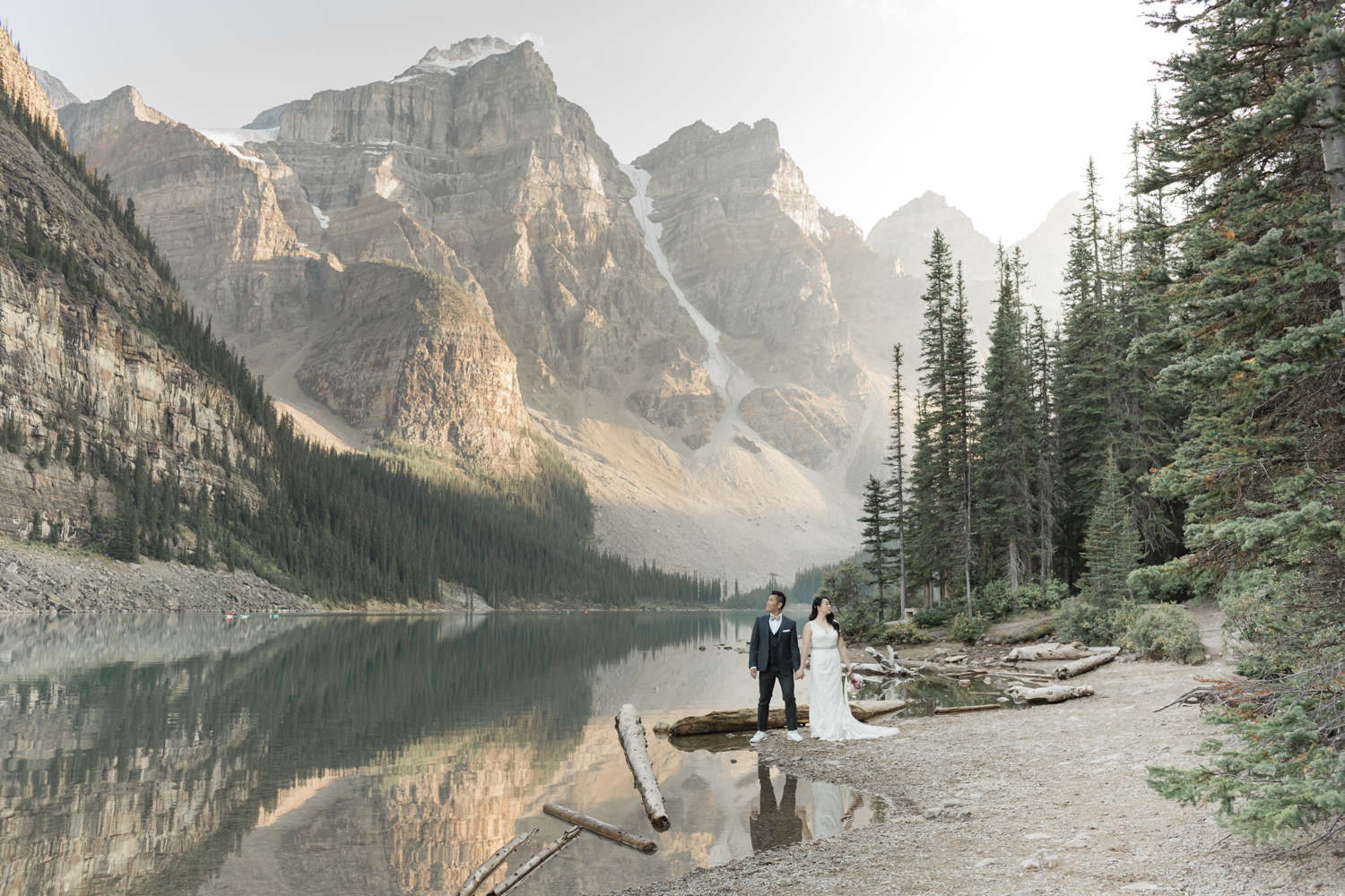 Couple holding hands looking in opposite directions at the base of the valley of the ten peaks at lake moraine in banff national park