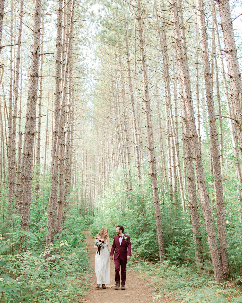 Walking along the trail hand in hand towards their ceremony spot near the waterfalls along the high falls trail in Algonquin's southgate for their Ontario elopement 