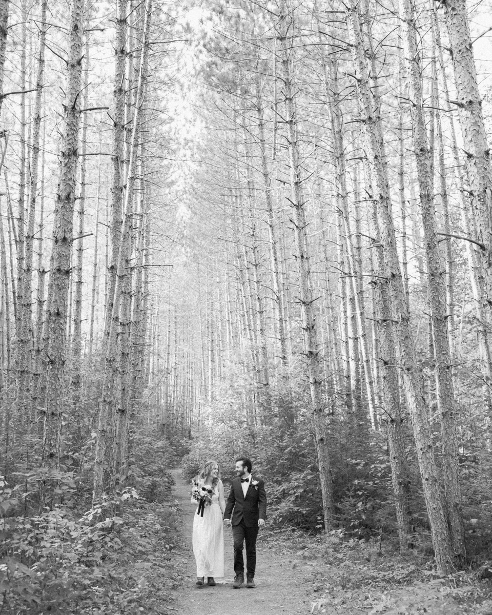 Walking along the trail hand in hand towards their ceremony spot near the waterfalls along the high falls trail in Algonquin's southgate for their Ontario elopement 