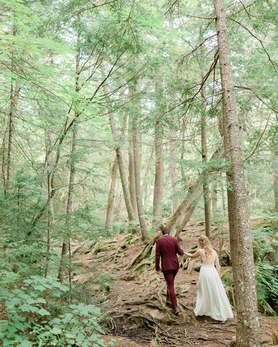 Walking along the trail hand in hand towards their ceremony spot near the waterfalls along the high falls trail in Algonquin's southgate for their Ontario elopement 