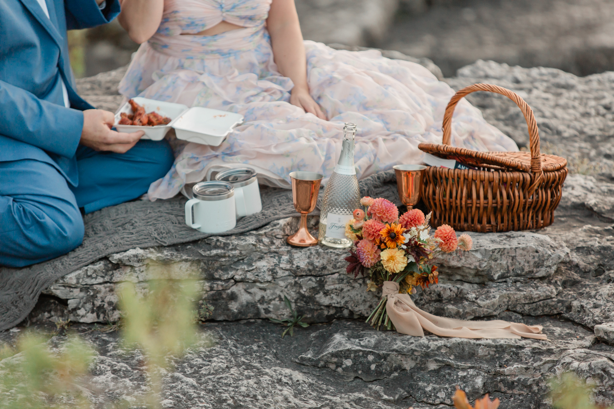 A couple celebrating with a wings and champagne picnic post vow ceremony during their Ontario wedding