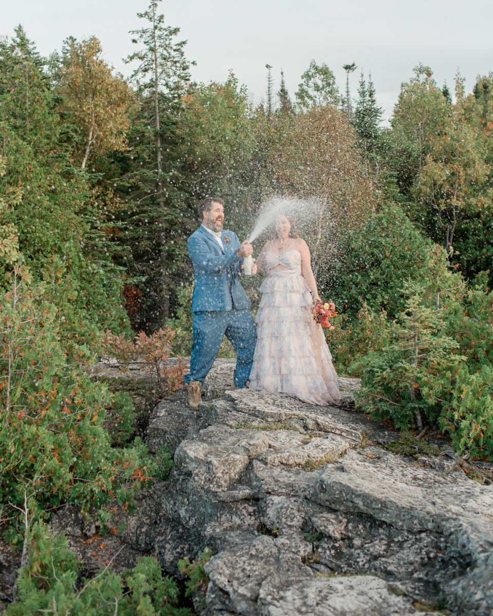 Katie and John pop champagne near the Grotto and Indian Head Cove for their Ontario elopement
