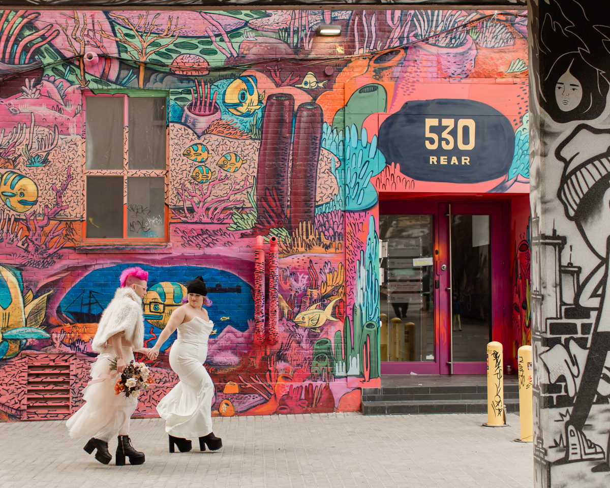 June and Trevor walk to take wedding portraits in graffiti alley 