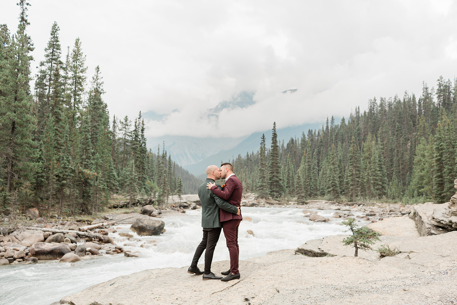 A couple in formal wedding attire kisses during their elopement at Mistaya Canyon.