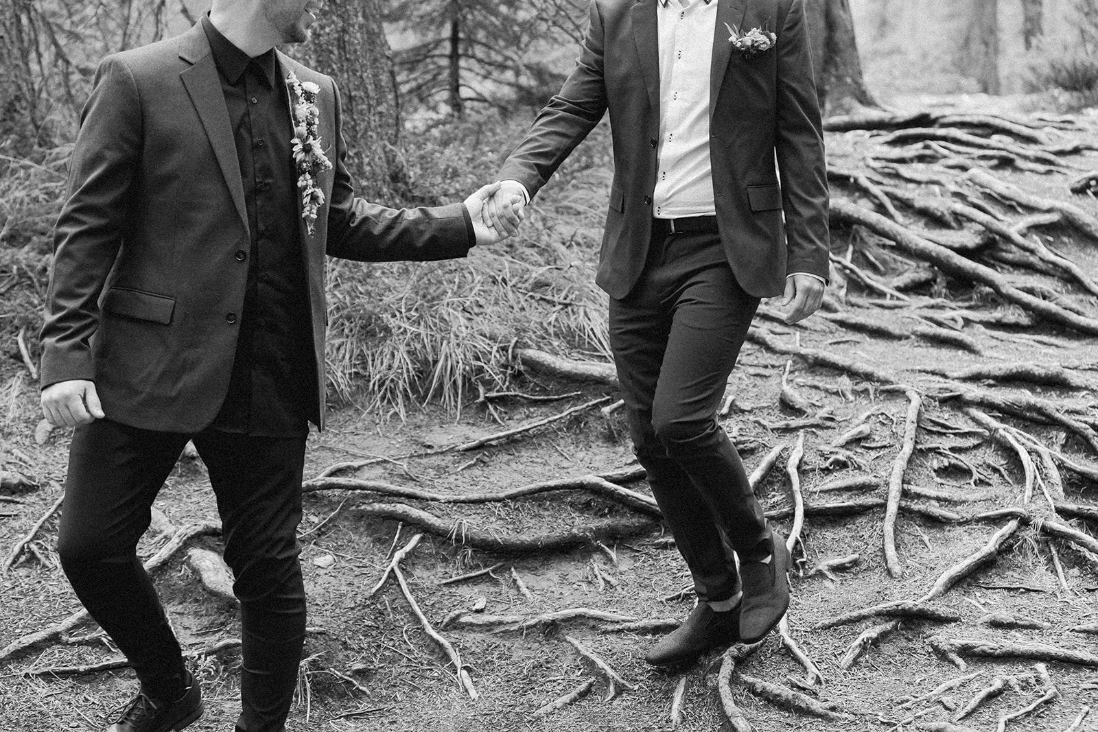 A man leads his groom through a forest in Mistaya Canyon during their elopement near Banff.