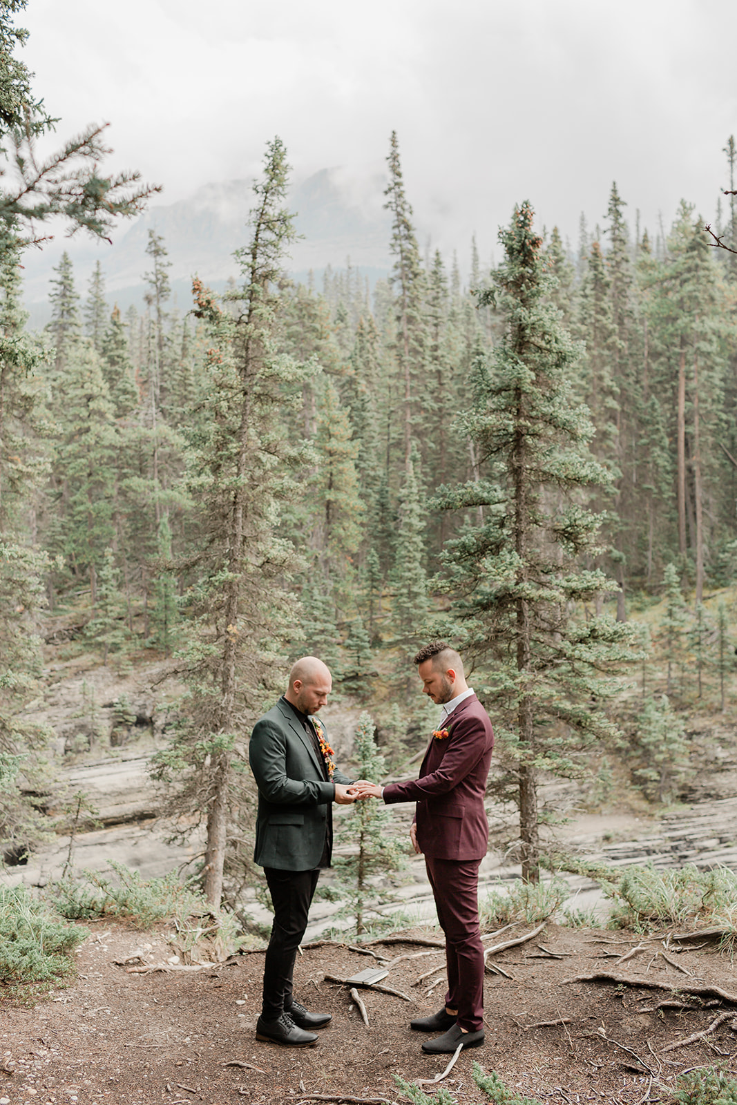 A Mistaya Canyon elopement couple exchanges rings with one another during an intimate outdoor ceremony near Banff.