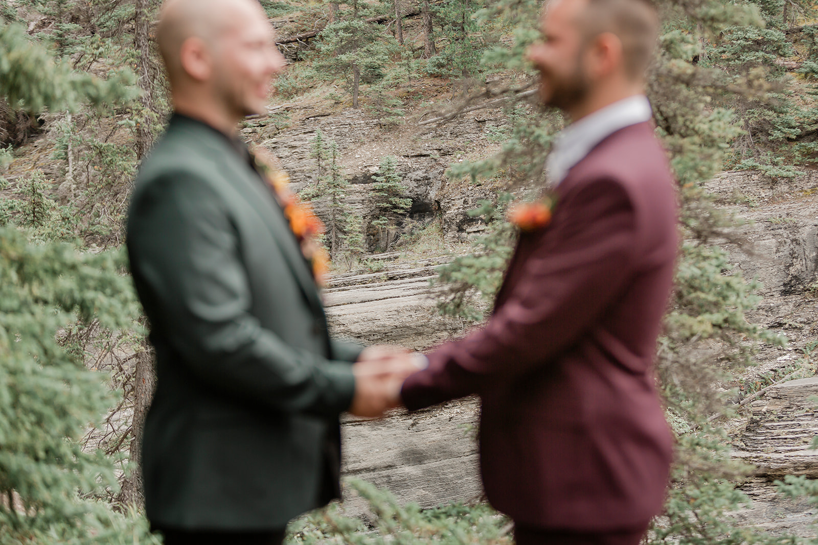 A Mistaya Canyon elopement couple holds hands during an intimate outdoor vow ceremony near Banff.